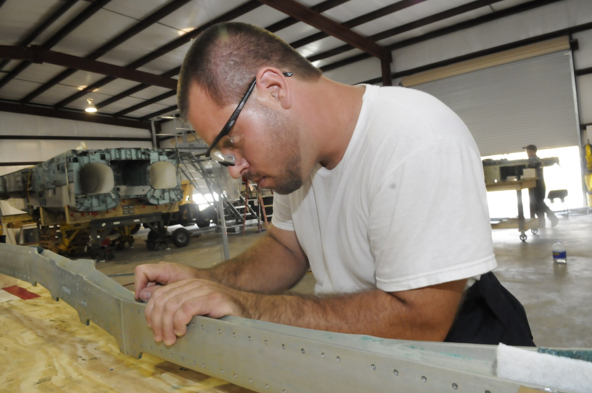 Ben Rogers strips paint and primer off  a longeron so it can be sent off for analysis. U. S. Air Force photo by Sue Sapp