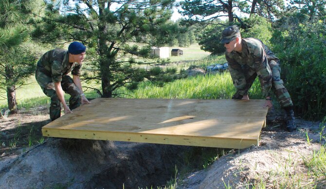 Cadet 2nd Class Christopher Molstad and Cadet 1st Class Justin Fisk ready Operation Warrior foxholes with overhead defenses. The area services ground combat tactics. (U.S. Air Force photo/Ann Patton)