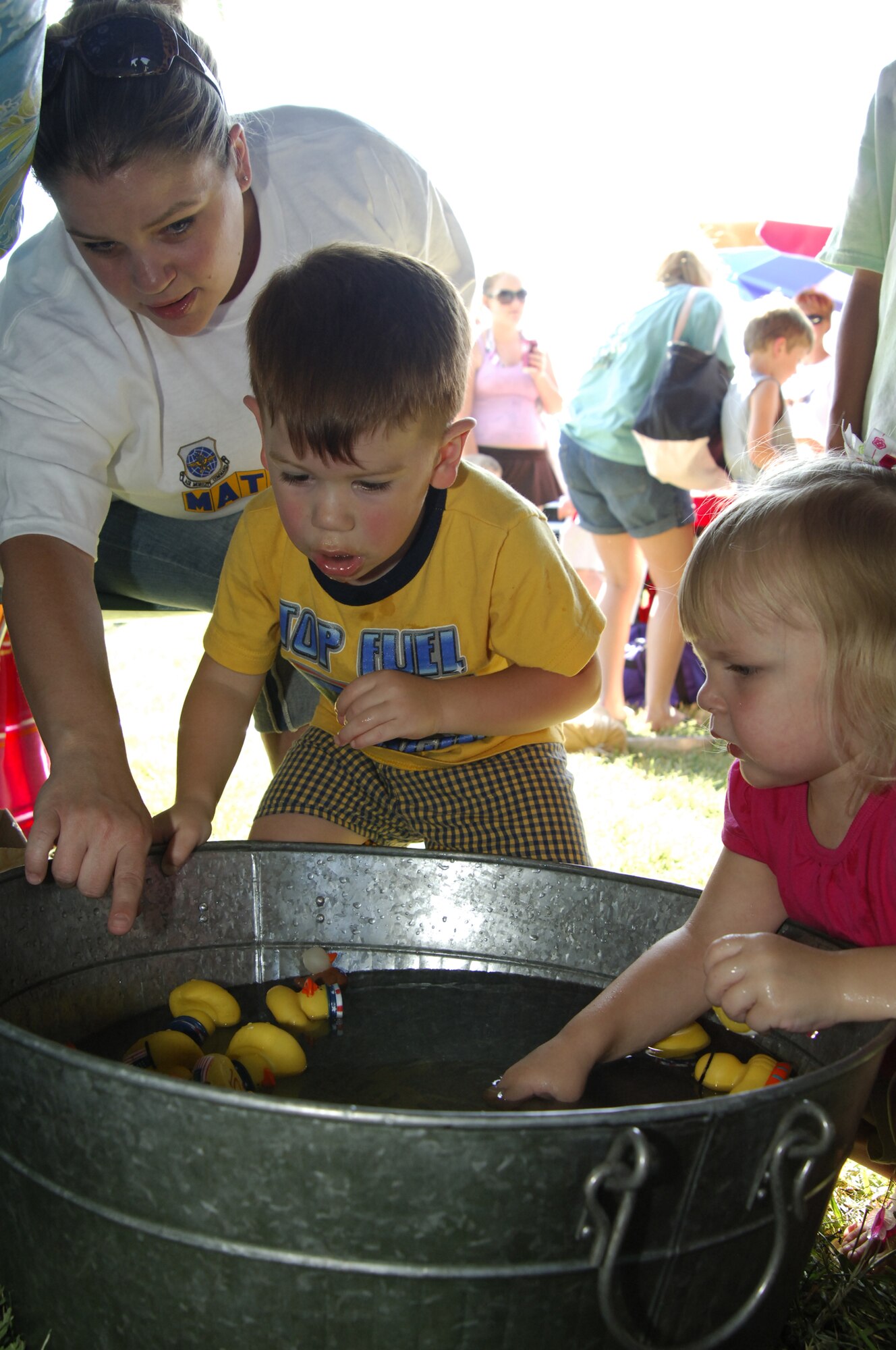 MCCONNELL AIR FORCE BASE, Kan. -- Debbie Speed, a member of the McConnell Enlisted Spouses Club, shows her daughter Miranda, 2, and Louie R. Flint III, son of Staff Sgt. Louie R. Flint II, 22nd Civil Engineering Squadron, and Melissa Flint, how to pick a duck to win prizes.  The McConnell Enlisted Spouses Club sponsored some children games for the Freedom Celebration Beach Party, July 2. (Photo by Tech. Sgt. Chyrece Campbell)
