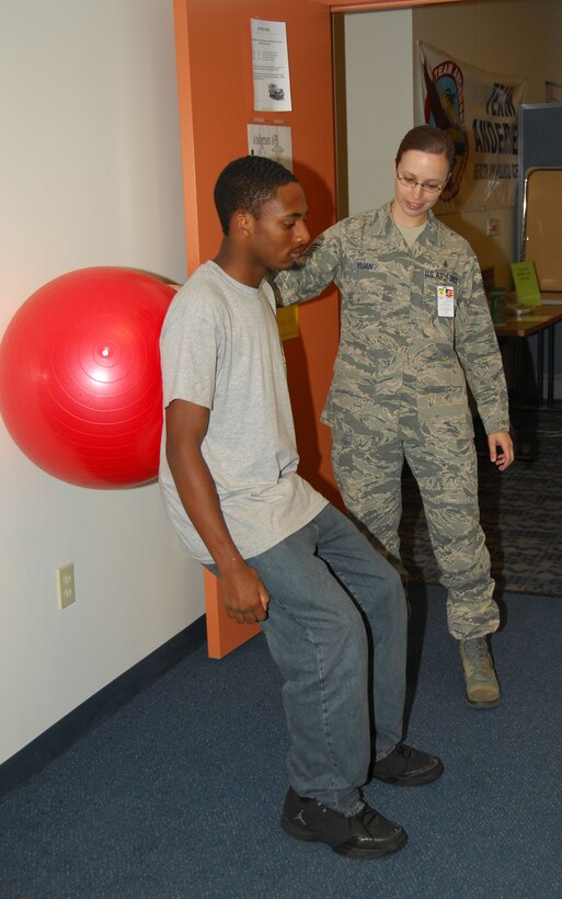 ANDERSEN AIR FORCE BASE, Guam - Tech. Sgt. Evita Yuan, 36th Medical Operations Squadron physical therapy technician, instructs Jordan Walker, a summer hire for the physical therapy clinic, to do a squat using an exercise ball here July 1. The clinic treats more than 250 patients per month. (U.S. Air Force photo by Senior Airman Shane Dunaway)