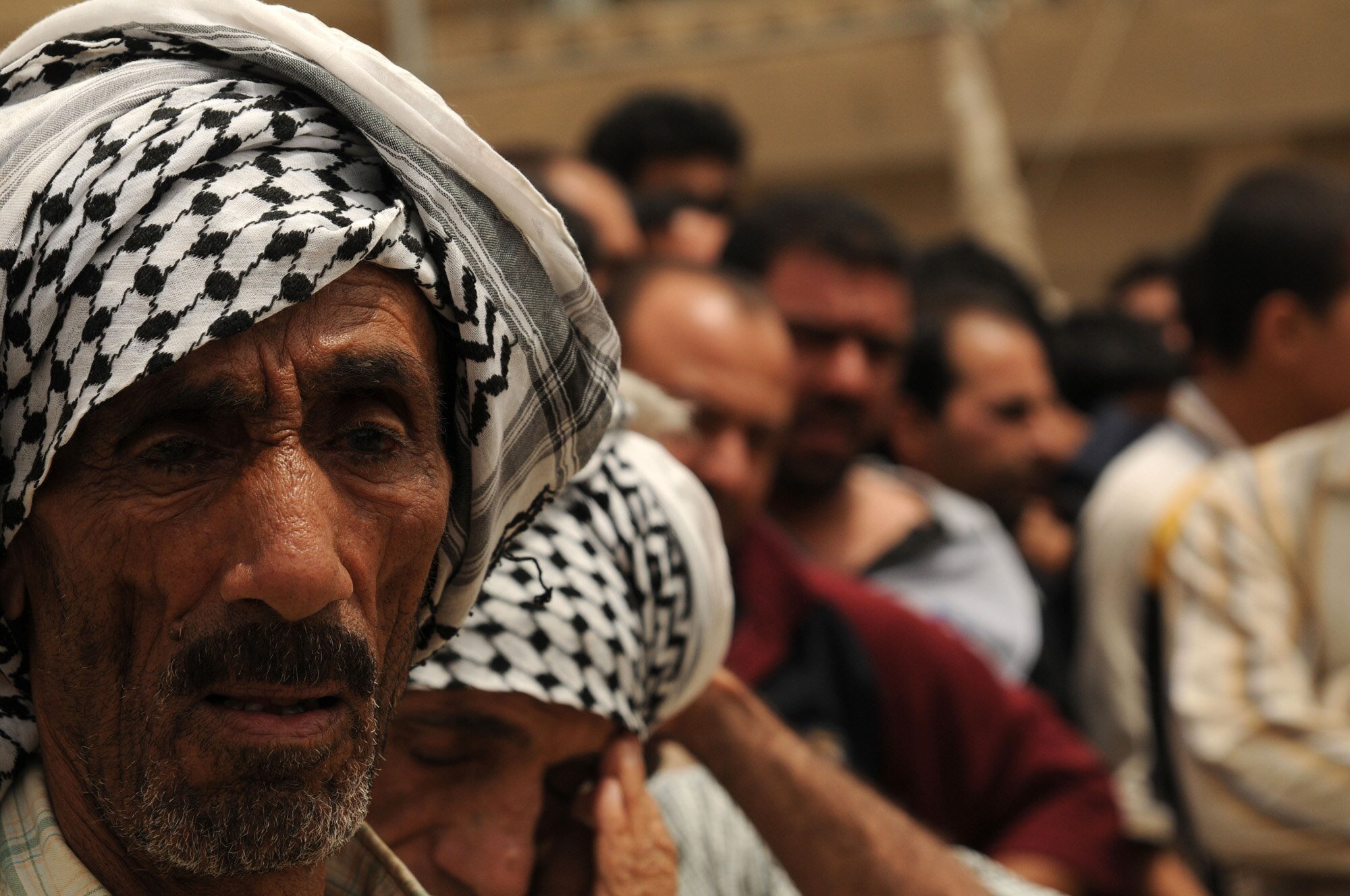 A man waits in a long line of men outside an abandoned school to receive food, water and medical supplies from the Iraqi Army 42nd Brigade 11th Division in Sadr City, Baghdad, Iraq on May 8, 2008. The Iraqi Army handed out relief supplies and provided medical care in an effort to help the people in the district. More than two hundred and fifty people showed up to receive free food and medical supplies. 
