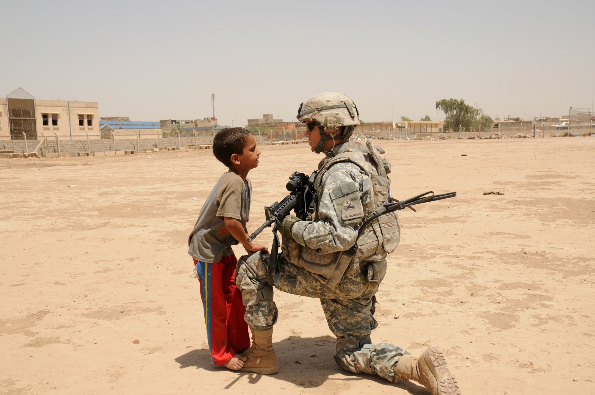 U.S. Army Task Force Regulars 1st Battalion, 6th Infantry Regiment SSG Fred Hampton of Lexington, Ky., kneels on a knee to talk with a young Iraqi boy at the future site of Regular 6 Park in the Thawra 1 section of the Sadr City district of Baghdad on June 20, 2008.
