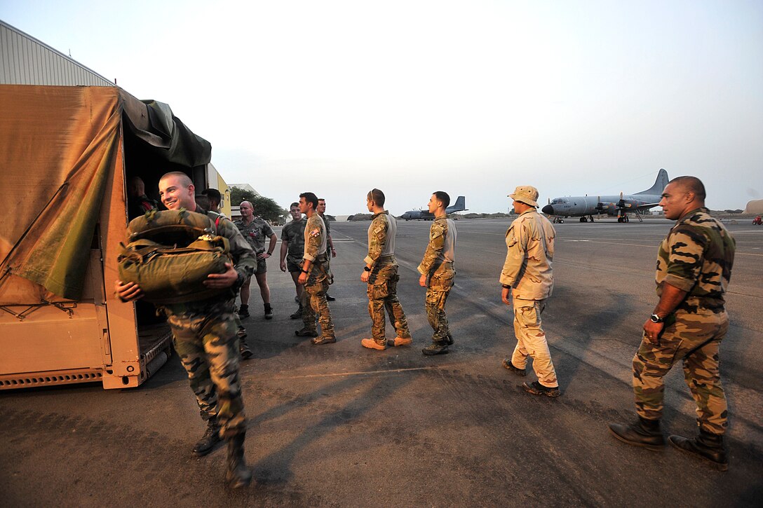 U.S. airmen and French Foreign legionnaires wait to receive parachutes at a French military base in Djibouti, June 30, 2009.