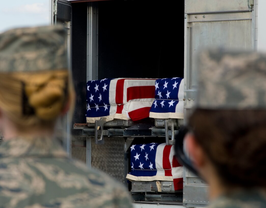 Air Force personnel watch as the caskets of six fallen soldiers are loaded onto a waiting hearse on Dover Air Force Base, Del., July 8, 2009.
