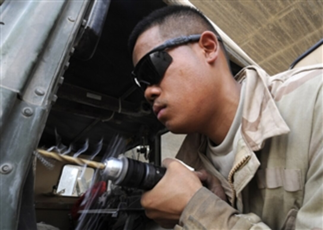 U.S. Army Spc. Richard Cavasug, assigned to the 3rd Brigade, 215th Brigade Support Battalion, 1st Cavalry Division, drills a hole to replace a hinge on a Humvee door at a base mechanic shop at Forward Operating Base Marez in Mosul, Iraq, on July 7, 2009.  