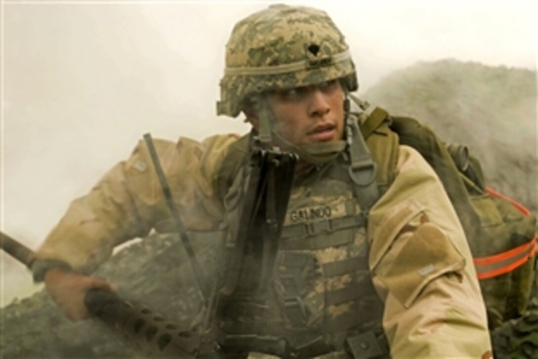 U.S. Army Spc. Andres Galindo adjusts the barrel of a .50 caliber machine gun while under simulated fire during the situational training exercise for the NCO of the Year competition in Baumholder, Germany, June 30, 2009. Galindo is assigned to the 357th Air Missile Defense-Detachment. Competitors were required to wear their mission-oriented protective posture gear.