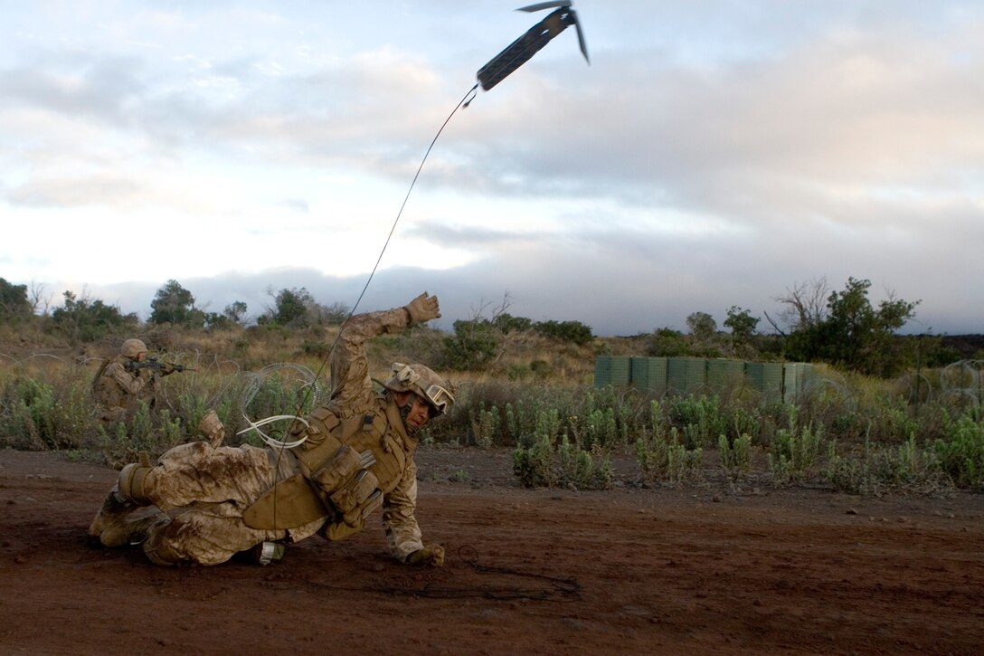 Lance Cpl. Danny Martinez, 1st Platoon, Bravo Company, 1st Battalion, 3rd Marine Regiment, throws a makeshift grappling hook into a concertina wire roadblock to pull it aside for a casualty evacuation vehicle to enter the enemy compound.::r::::n::
