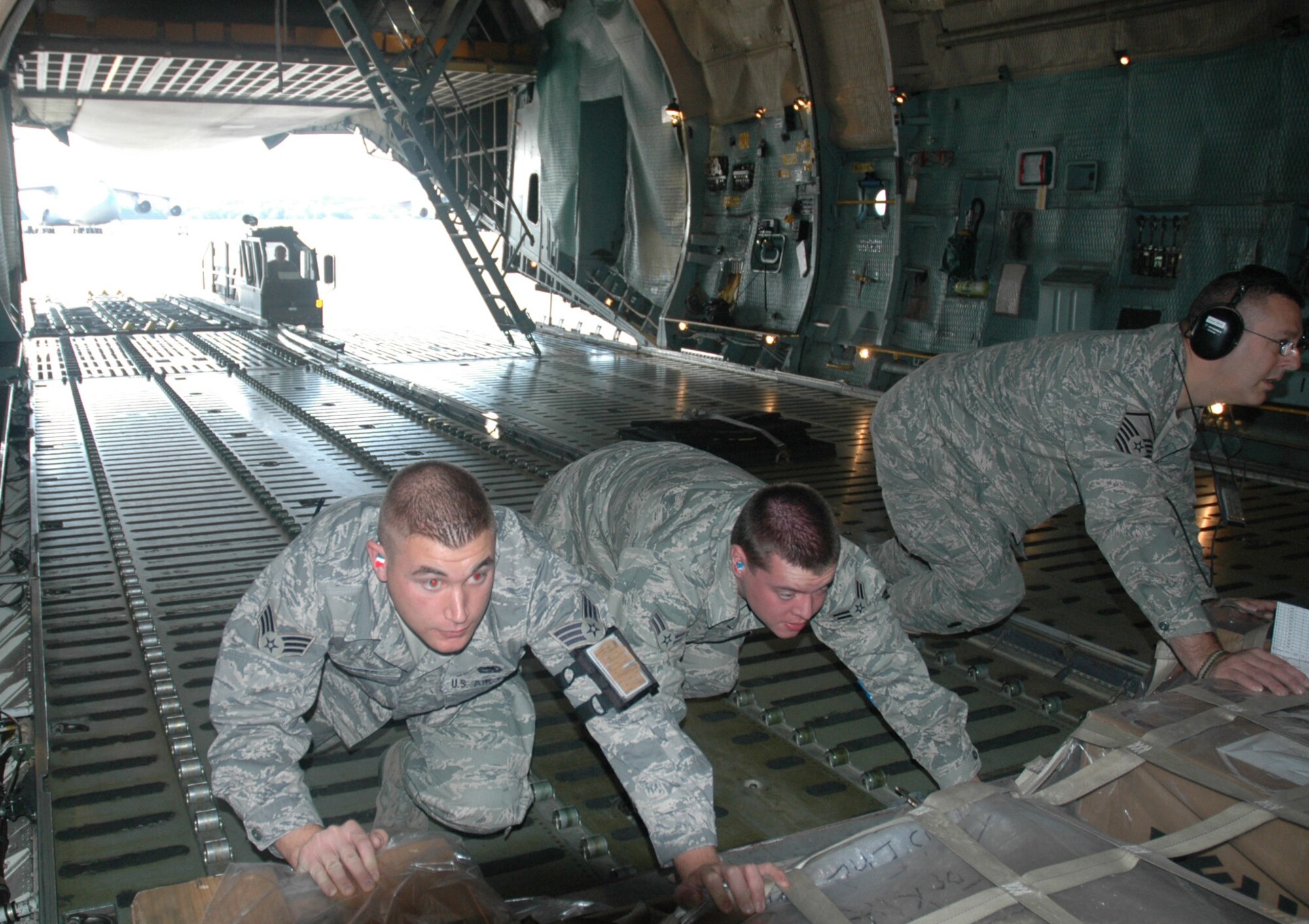 Airmen with Westover's 42nd Aerial Port Squadron load communications gear aboard a Patriot Wing C-5 July 10. From left to right are Senior Airman David Adamiec, Airman 1st Class Alexander Carmel, and Master Sgt. Dan Witt. Westover's crews and aircraft deliver cargo worldwide as part of the Air Force Reserve's strategic airlilift force. (US Air Force photo/Tech. Sgt. Andrew Biscoe)