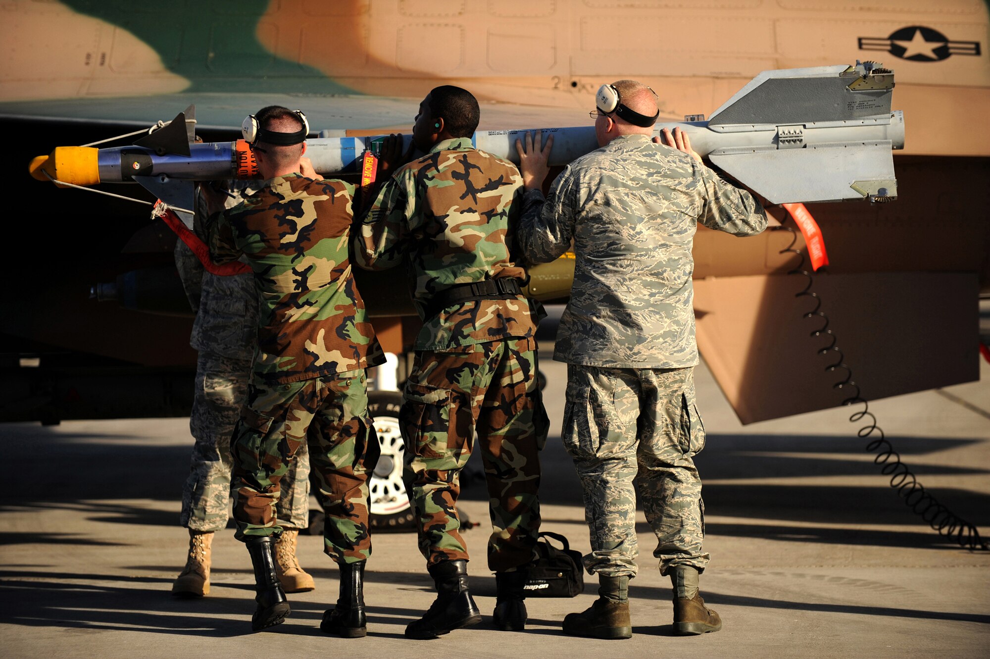 (left to right) Airman 1st Class Benjamin Whitfield, Staff Sgt. Cir Thomas and Senior Airman Casey Frye from the 57th Aircraft Maintenance Squadron, Viper AMU load an AIM-9 air to air missle on a F-16 Falcon during a weapons load competition at Nellis Air Force Base, Nev., on July 8, 2009. Weapons load competitions are conducted bi-monthly to keep Airman sharp while recognizing a job well done.  Load Crews are evaluated for use of the checklist, safety, and overall speed.  (U.S. Air Force Photo/Tech. Sgt. Michael R. Holzworth)

