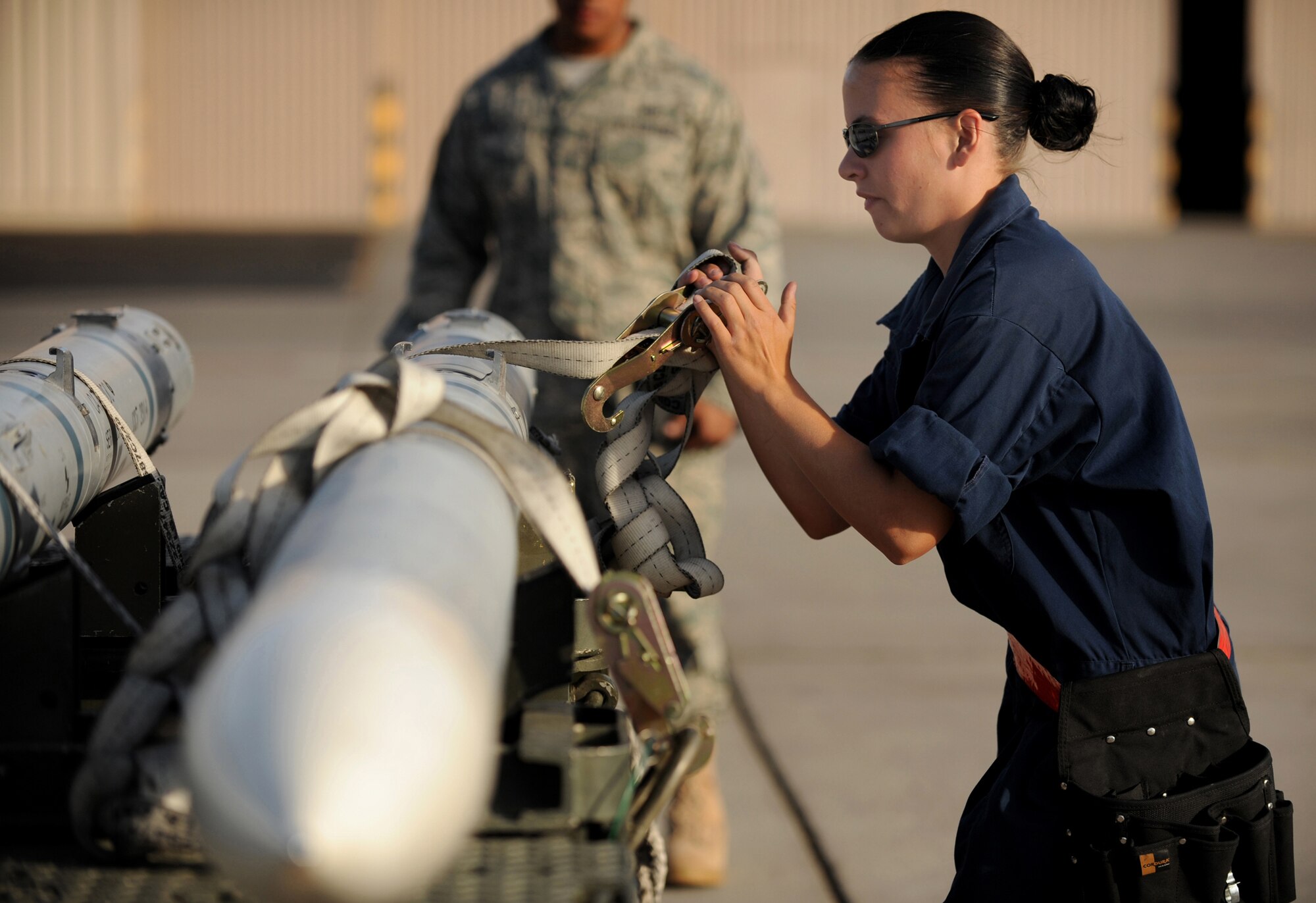 Airman 1st Class Kayce Stout from the 57th Aircraft Maintenance Squadron, Eagle AMU removes the cargo strap from an AIM-120 air-to-air tactical missile during a weapons load competition at Nellis Air Force Base, Nev., on July 8, 2009. Weapons load competitions are conducted bi-monthly to keep Airman sharp while recognizing a job well done.  Weapons Load Crews are evaluated for use of the checklist, safety, and overall speed. (U.S. Air Force Photo/Tech. Sgt. Michael R. Holzworth)

