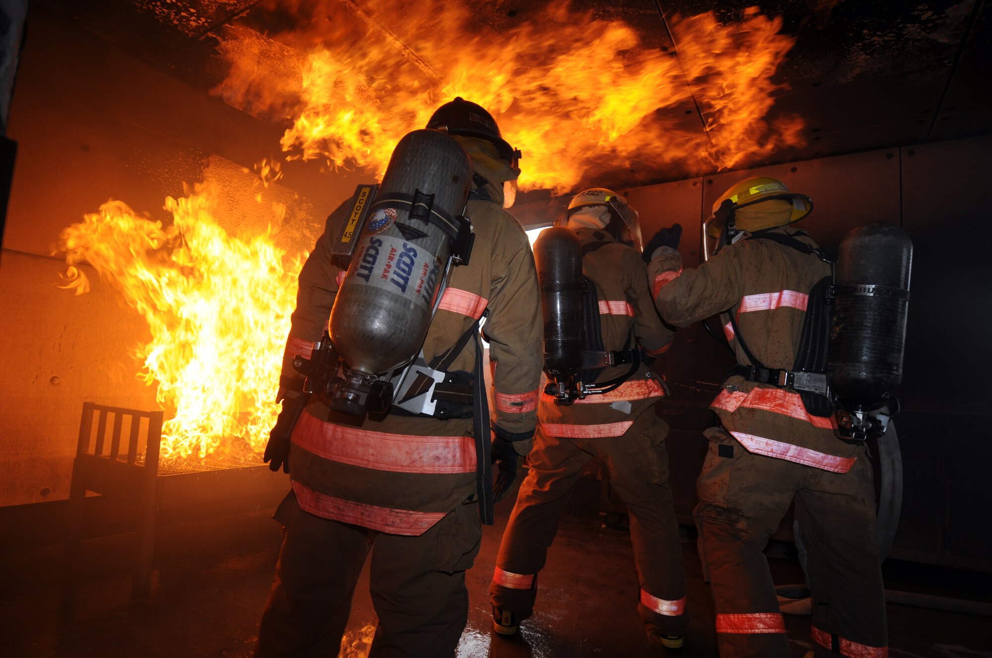 Danny Hebert, an instructor at the fire academy and student firefighters  Airman 1st Class Adam Ziehr  and Airman Dale Kuberski  prepare to put out a fire during block 4 (fire ground operations) of firefighter training. (U.S. Air Force photo by Tech. Sgt. John Barton) 
