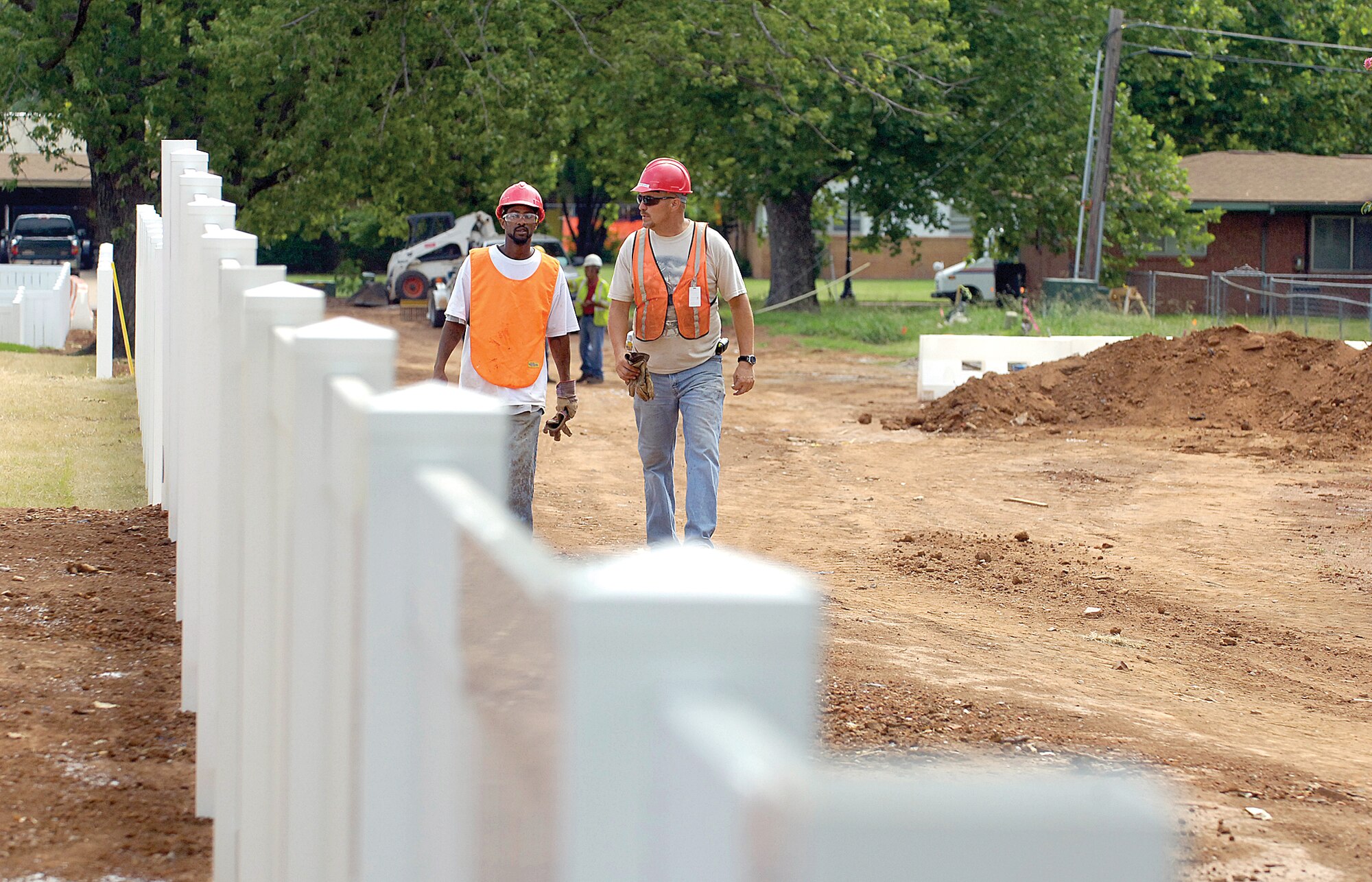 Construction crews walk along a new fence line behind homes being built along Twining. Older homes along McNarney are seen in the background. (Air Force photo by Margo Wright)