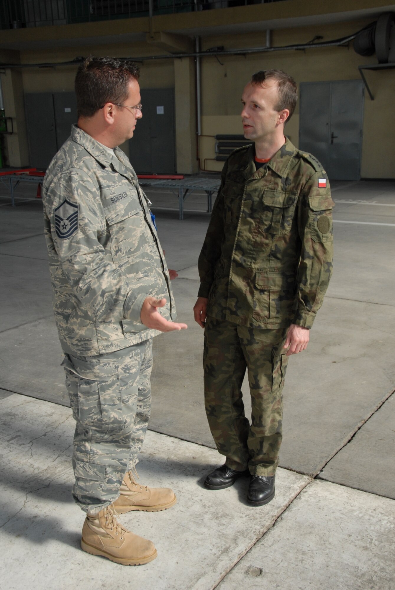 POWIDZ AIR BASE, Poland--Master Sgt. Peter Schussler, 182nd Guidance and Control Shop Chief, discuss C-130 avionics and the diversity of Polish and American culture with Capt. Dawid Florczak, 13th Squadron Avionics Shop Commander during a recent visit by the Peoria Air National Guard to Powidz Air Base, Poland. Schussler called his experience 'remarkable' when he compared careers with Florczak. (Photo by Tech Sgt. Shane Hill)
