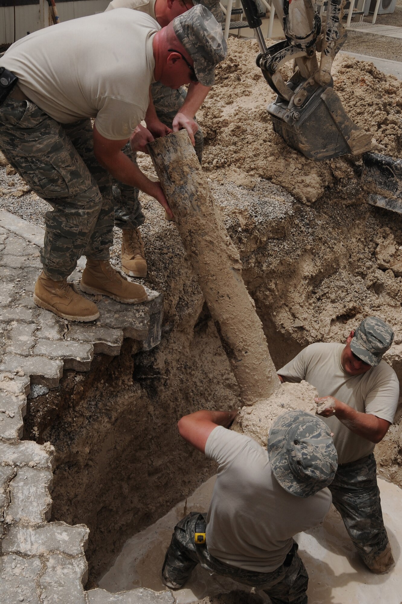 SOUTHWEST ASIA - Staff Sgt. Aaron Johnson and Airman 1st Class Justin Vaughn remove a valve box and pass it up to Tech Sgt. Klinton Bruck and Staff Sgt. Adam Hitchcock, to uncover a pipe leak, July 6 in Southwest Asia. The valve box protects the valve stem. The pipe sprung a leak when the mechanical flange that connects the valve to the pipe lost its seal. All four Airmen are utility craftsmen with the 380th Expeditionary Civil Engineer Squadron. (U.S. Air Force photo by Senior Airman Brian J. Ellis) 
