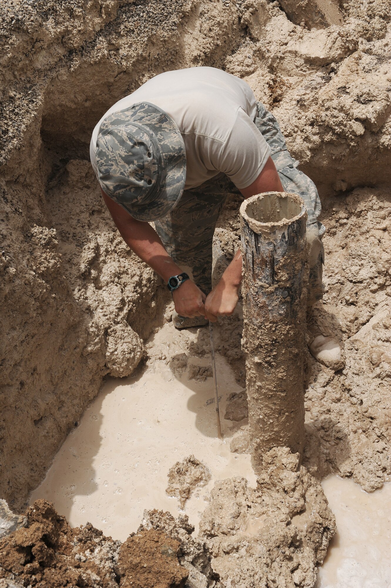 SOUTHWEST ASIA - Airman 1st Class Justin Vaughn, a 380th Expeditionary Civil Engineer Squadron utilities craftsman, uses a metal probe to see how deep a broken water pipe is from the surface, July 6 in Southwest Asia. The pipe sprung a leak when the mechanical flange that connects the valve to the pipe lost its seal. (U.S. Air Force photo by Senior Airman Brian J. Ellis) 