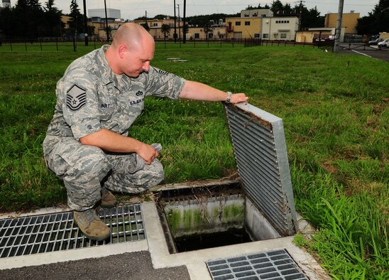 Master Sgt. Dennis Holt checks standing water in a storm drain for mosquito larva on the airfield at Yokota Air Base, Japan. Sergeant Holt is the NCO in charge of entomology with the 374th Civil Engineer Squadron. To control and prevent the spread of mosquitoes, there are several easy steps everyone should follow; remove, repair, or empty everything that could breed mosquitoes. Residents should also repair door and window screens to keep out mosquitoes. To prevent the influx of mosquitos, the base self-help store provides base residents insecticides specifically labeled for controlling adult mosquitoes. (U.S. Air Force photo/Airman First Class DevinDoskey) 