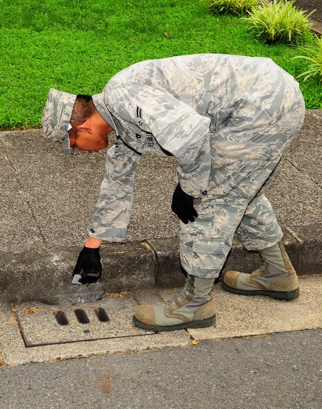 YOKOTA AIR BASE, Japan -- Airman First Class Perry Neang, 374th Civil Engineer Squadron Pest Management Apprentice, checks a storm drain for standing water. When standing water is discovered, a chemical treatment is performed to break the normal life cycle of the mosquitoes. The chemical insect growth regulator stops the development of a mosquito from the larva to adult stage and is one of the most effective forms of mosquito control. To control and prevent the spread of mosquitoes, there are several easy steps everyone should follow; remove, repair, or empty everything that could breed mosquitoes.  Residents should also repair door and window screens to keep out mosquitoes. To prevent the influx of mosquito's the base self-help store provides base residents insecticides specifically labeled for controlling adult mosquitoes. (U.S. Air Force photo/Airman First Class DevinDoskey)
