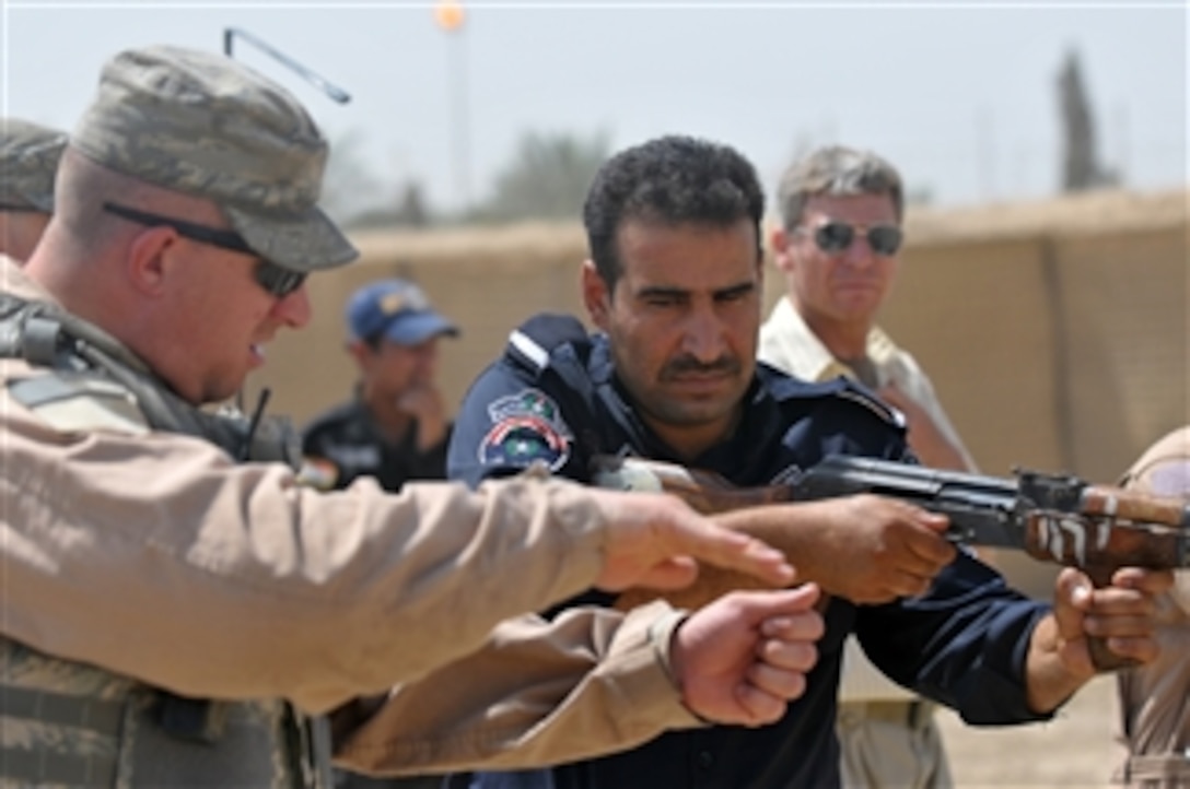 A U.S. Air Force airman with the 732nd Expeditionary Security Forces Squadron, attached to the 93rd Military Police Battalion, instructs an Iraqi Police officer from the Abu Ghraib district during range training at Forward Operating Base Mahmudiyah, Iraq, on July 8, 2009.  