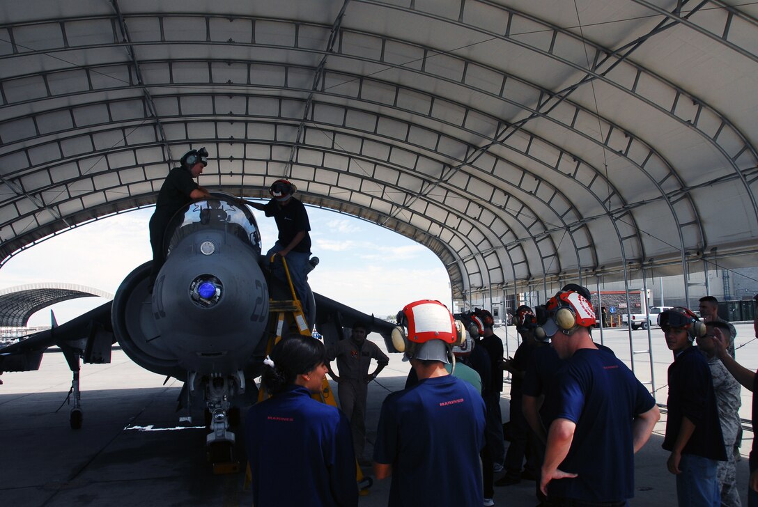 Sgt. Brandon Dills, Marine Attack Squadron 311 seat maintainer, answers poolees' questions during their visit to the flight line of the Marine Corps Air Station in Yuma, Ariz., July 10, 2009. Of the 15 poolees from the local recruiting station, three are slated for aviation maintenance jobs in the Corps. "It's really cool to see the plane that I might be working on," said Rafael Rojas, 19, who is scheduled to leave for boot camp in early 2010. The potential Marines toured the squadron hangar, learned about squadron and Harrier history, got an up-close view of a Harrier and visited the station's flight simulator.