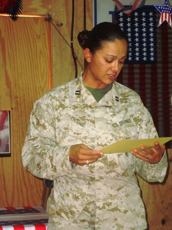 Capt. Natalie Trogus, Combat Logistics Battalion 7, 2nd Marine Logistics Group (Forward)'s outgoing camp commandant for Camp Korean Village, Iraq, reads a certificate of appreciation during a transfer of authority ceremony July 11, 2009, aboard the camp.  Trogus transferred authority of the camp to Army Capt. Michael Partin, one of three officers of the 3rd Expeditionary Sustainment Command taking over the duties of camp commandant. (Courtesy photo by Morale, Welfare and Recreation)