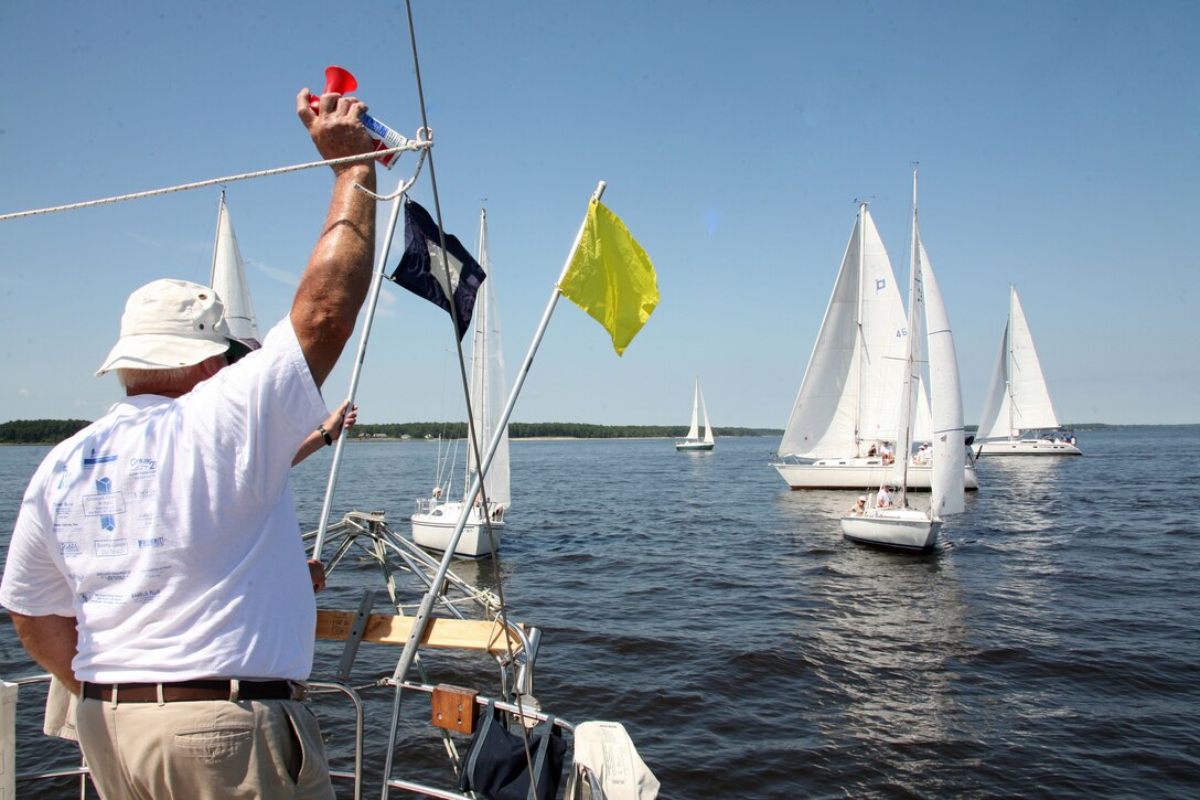 Ed “Sandy” Sanderson sounds a horn, signaling the start of a leg of the regatta. Sanderson is a member of the Hancock Yacht Club.