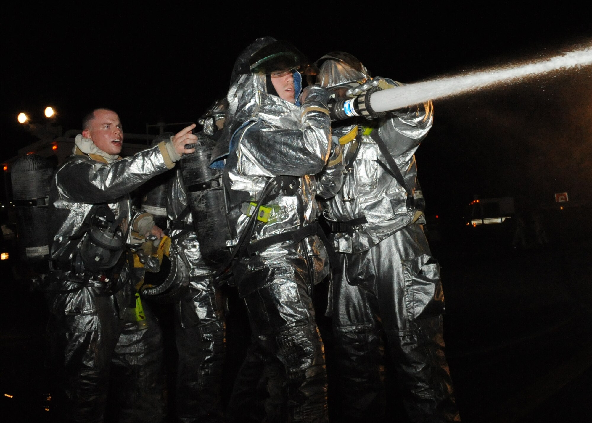 Members of the 379th Expeditionary Civil Engineer Squadron fire department aim a fire hose during an egress simulation exercise July 7 on the flightline in Southwest Asia. Training is conducted regularly to ensure all members of the unit are current on all Air Force training requirements and prepared to handle emergency situations as necessary.(U.S. Air Force photo/Tech. Sgt. Jason Edwards)