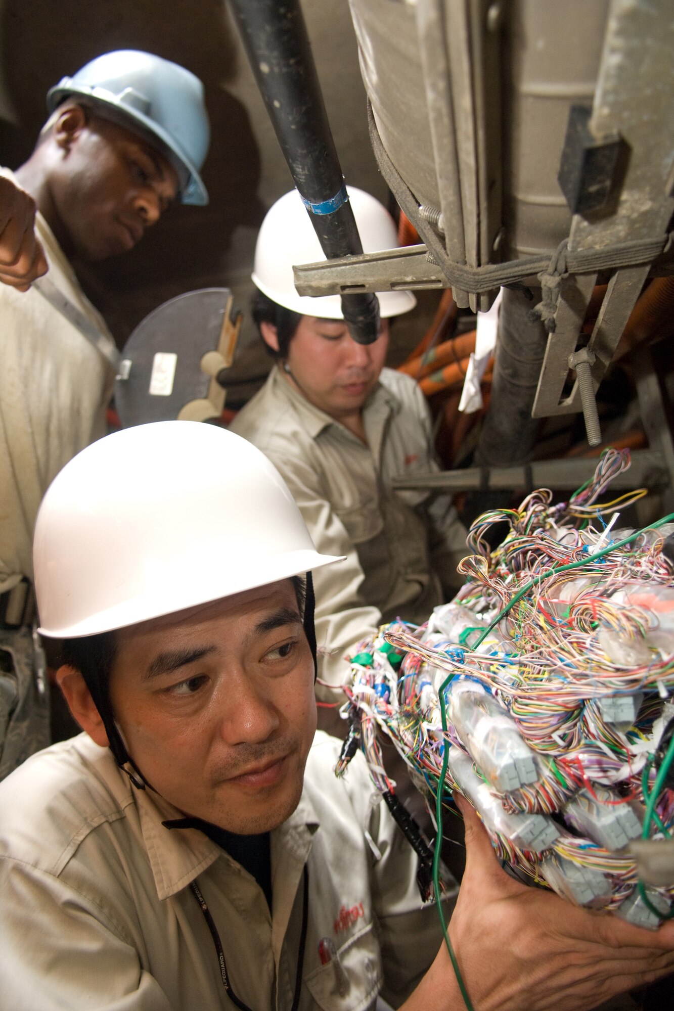 YOKOTA AIR BASE, Japan -- Senior Airman Lakendrick Fisher, 374th Communications Squadron Cable and Antenna Maintenance Shop, (left) and employees of the Japanese Telephone Cable Company repair telephone cables July 13 damaged during a fire on base earlier this year. Airman Fisher and his Japanese counterparts also installed more than 300 cables to support a new facility. (U.S. Air Force photo/Osakabe Yasuo)
