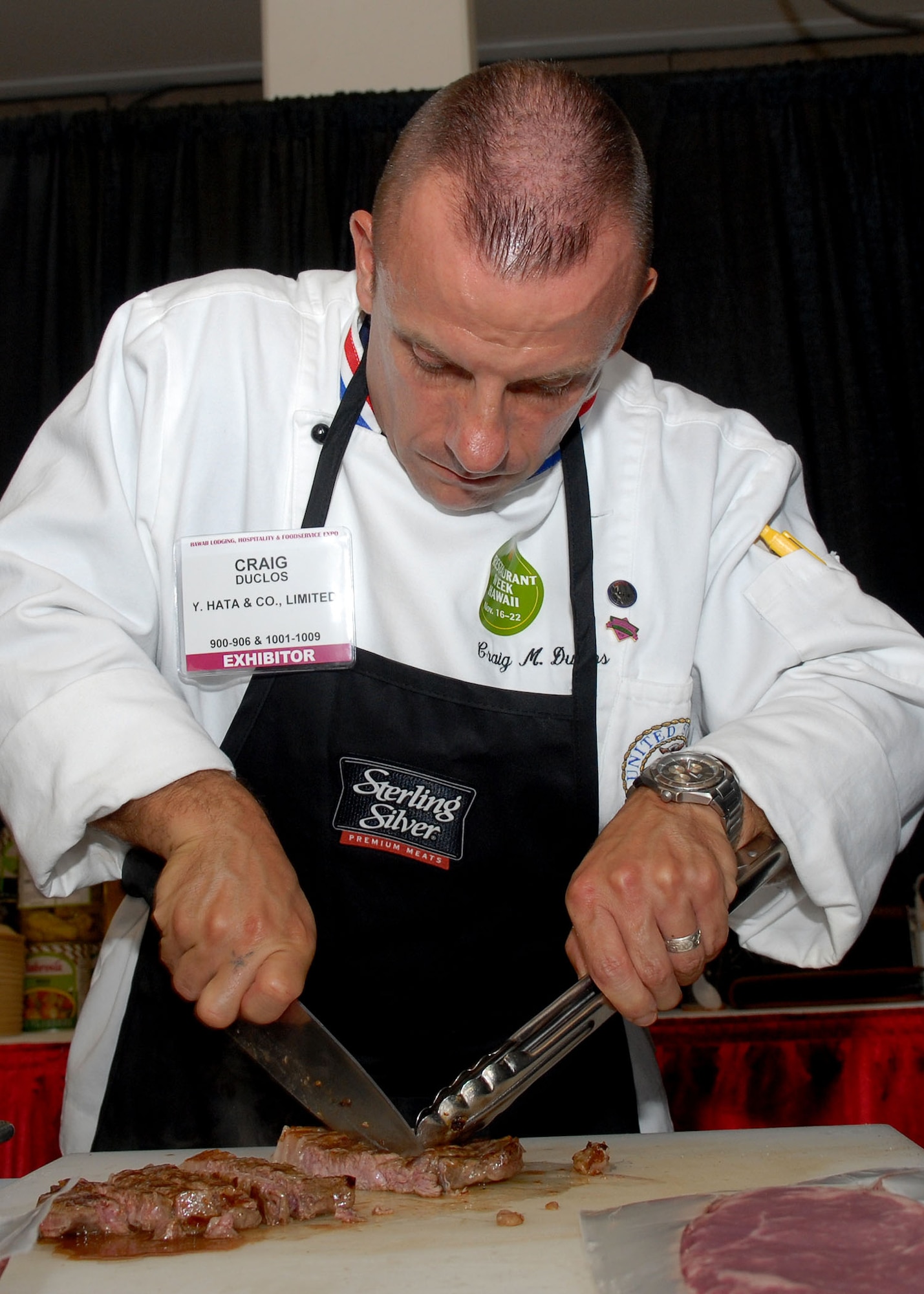 HONOLULU, Hawaii -- Master Sgt. Craig Duclos, Pacific Air Forces commander’s senior enlisted aide, cuts up "Del Monico" ribey steak at the 15th Annual Hawaii Lodging, Hospitality and Foodservice Exposition at the Neal Blaisdell Center in Honolulu, Hawaii July 9. Sergeant Duclos, from Hickam Air Force Base, Hawaii, participated in the expo by cooking and serving meat entrees such as shrimp, steak and swordfish.  (U.S. Air Force photo/Tech. Sgt. Jerome S. Tayborn)  