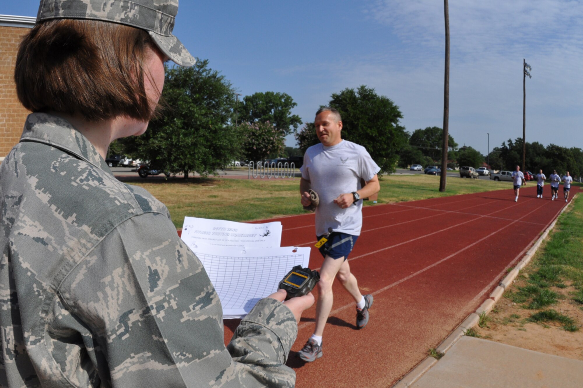 Maj. Ken Ratliff, 917th Mission Support Flight, commander, smiles with pride as he finishes the last lap of his annual fitness test and Capt. Stephanie Kennedy, 917th Wing, fitness coordinator, calls out his time on the outdoor track at Barksdale Air Force Base, La., July 12, 2009. The Air Force Fitness Test is designed to test the body composition, muscular strength/endurance and cardiovascular respiratory fitness of Airmen in the U.S. Air Force. As part of the “Fit to Fight” program, the Air Force adopted a more stringent physical fitness assessment; the new fitness program was established on January 1, 2004, and replaces the annual ergo-cycle test that Air Force used before. (U.S. Air Force photo/Tech. Sgt. Jeff Walston)