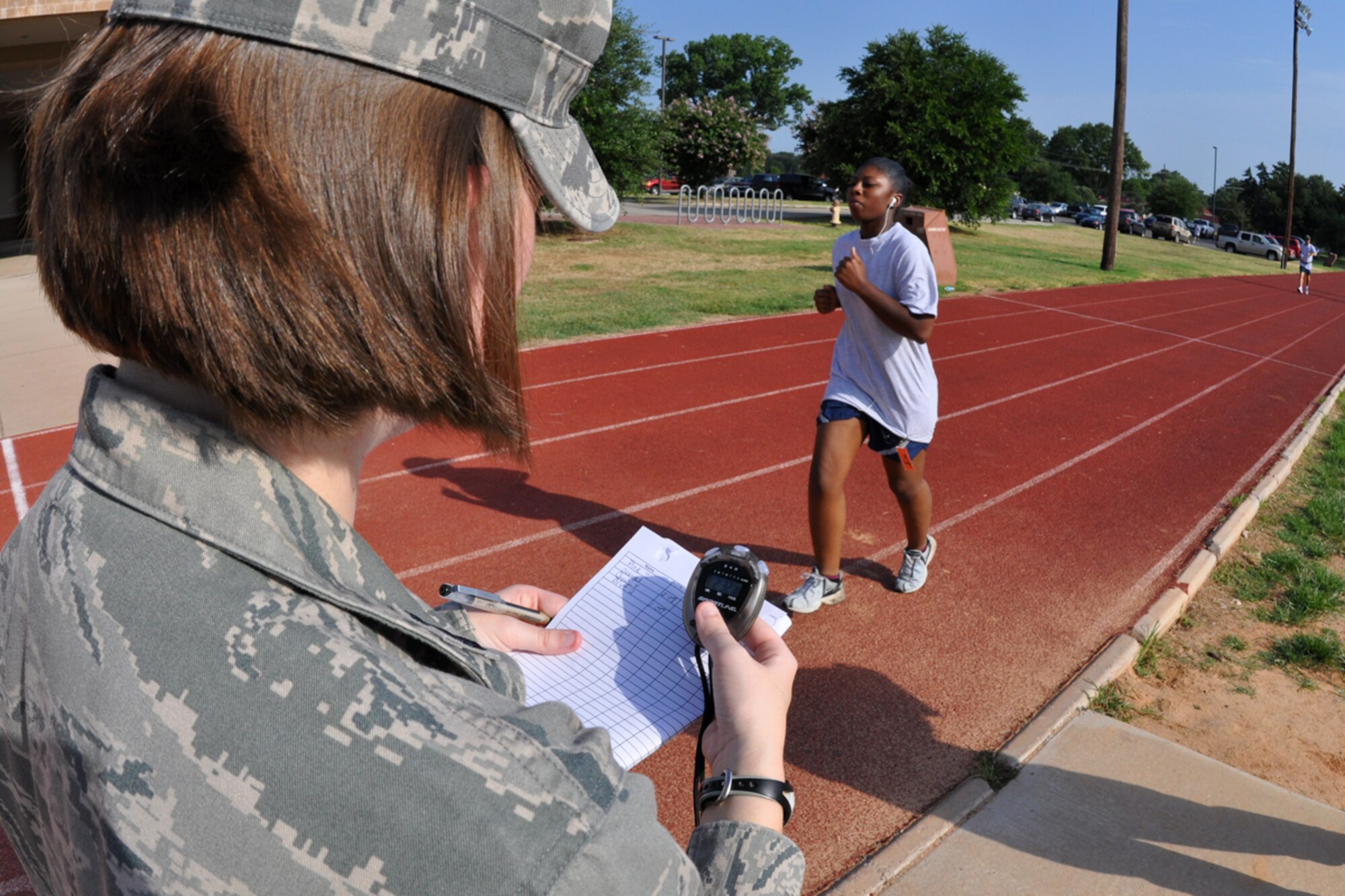 Finishing her first lap, Staff Sgt. Elisha Wood, 917th Civil Engineer Squadron, utilities system mechanic, passes Capt. Stephanie Kennedy, 917th Wing, fitness coordinator, and receives her lap time during her fitness test on the outdoor track at Barksdale Air Force Base, La., July 12, 2009. The Air Force Fitness Test is designed to test the body composition, muscular strength/endurance and cardiovascular respiratory fitness of Airmen in the U.S. Air Force. As part of the “Fit to Fight” program, the Air Force adopted a more stringent physical fitness assessment; the new fitness program was established on January 1, 2004, and replaces the annual ergo-cycle test that Air Force used before. (U.S. Air Force photo/Tech. Sgt. Jeff Walston)