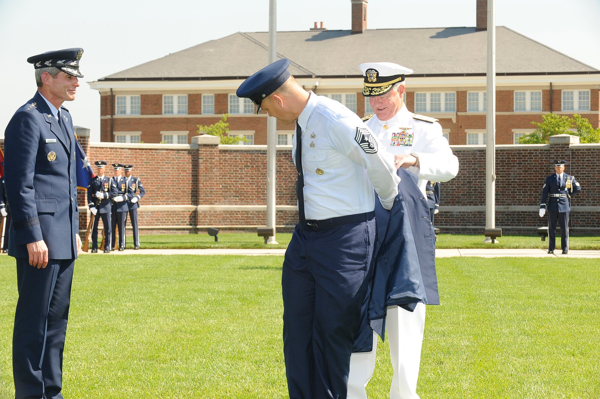 Navy Admiral Timothy J. Keating, U.S. Pacific Command commander, helps Chief Master Sgt. of the Air Force James A. Roy put on his service coat during an appointment ceremony June 30 at Bolling Air Force Base, D.C. 