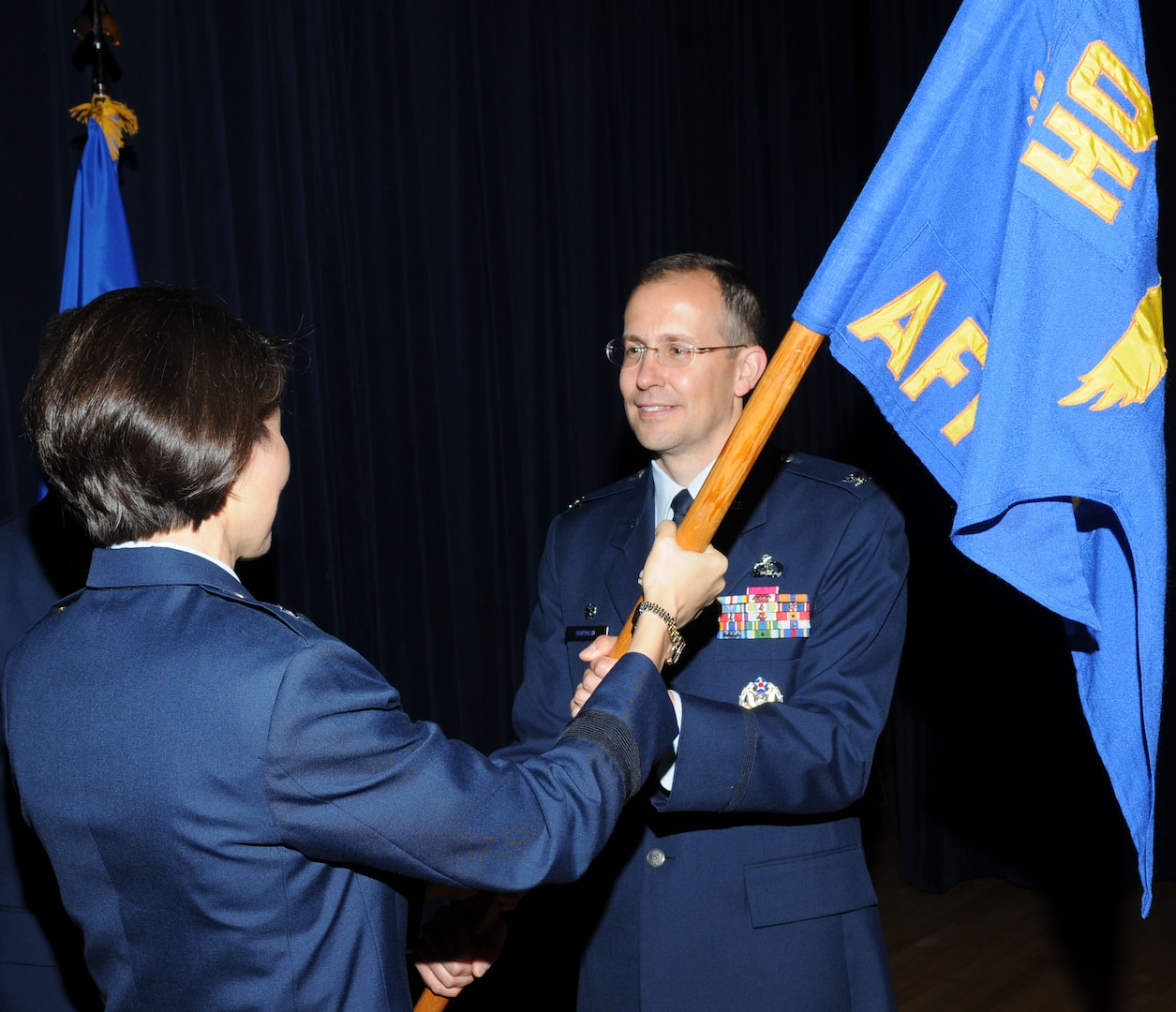 Col. Brian Norman, incoming Air Force Manpower Agency commander, takes the agency's guidon from Brig. Gen. Sharon Dunbar,  Director of Manpower, Organization and Resources, Deputy Chief of Staff for Manpower, Personnel and Services in Washington D.C., during a change of command ceremony June 30 at the Parr O'Club. (U.S. Air Force photo by Joel Martinez)