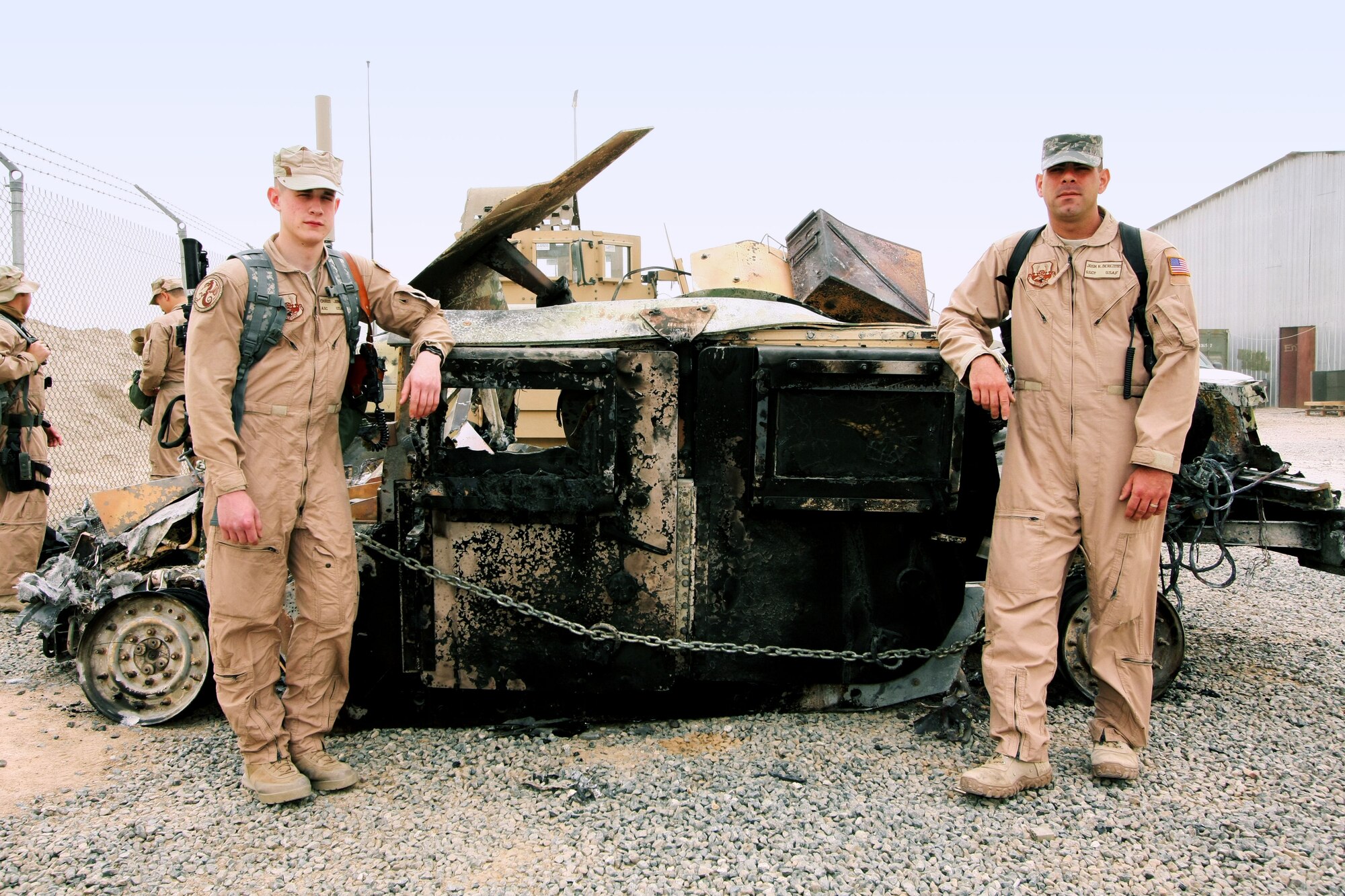 Tech. Sgt. Joshua Derezotes and Airman 1st Class Christopher
Jones, deployed with the 887th Expeditionary Security Forces Squadron, pose
by the burnt humvee after it was hauled inside the wire.  (Courtesy photo)
