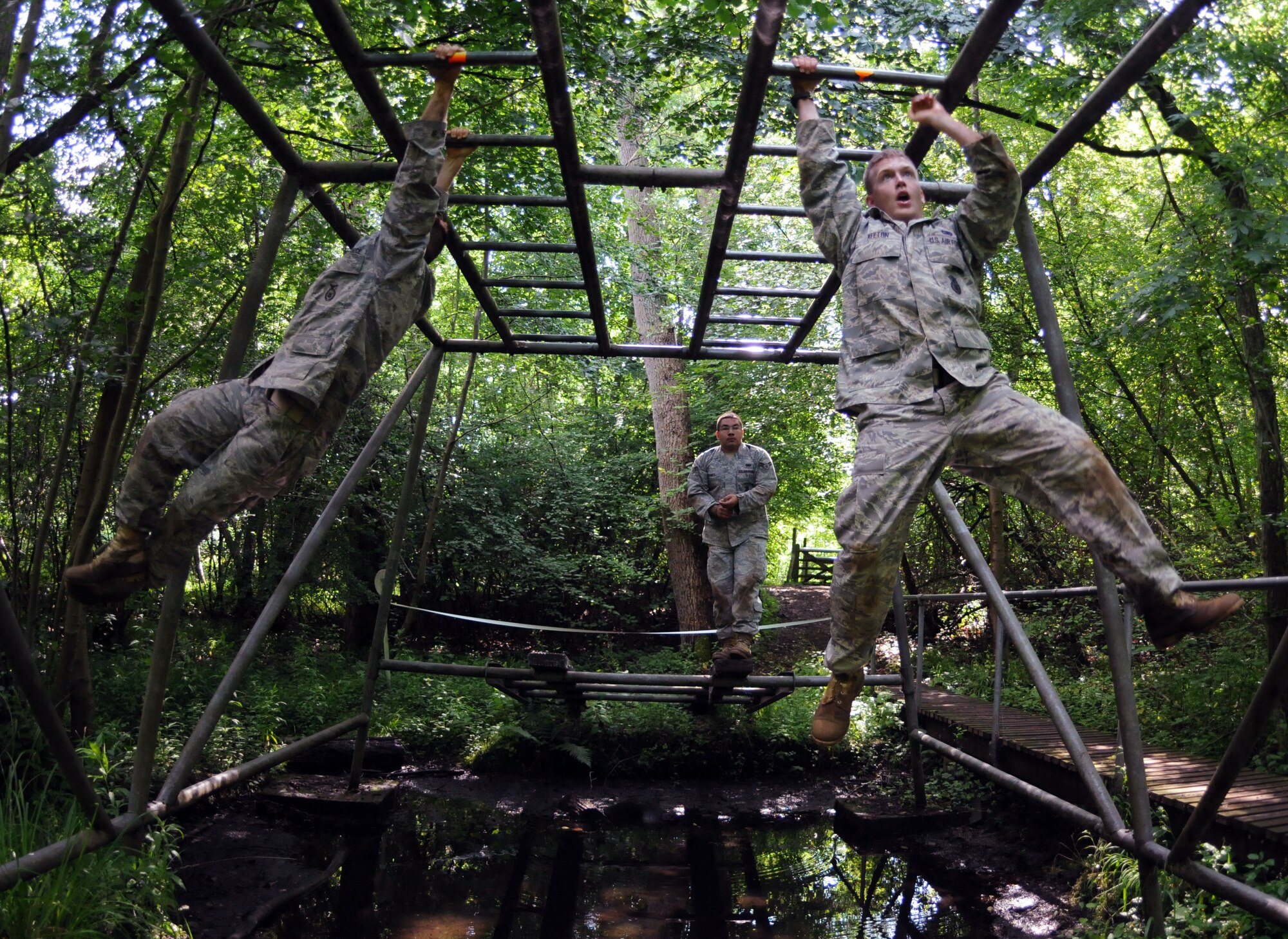 A group of Airmen from the 100th Security Forces Squadron swing over a muddy pit on monkey bars while training for the upcoming 2009 Air Mobility Rodeo competition.  A team of five Airmen from the 100th SFS trained for about 10 weeks to prepare for the biennial event.  (U.S. Air Force photo by Staff Sgt. Austin M. May)