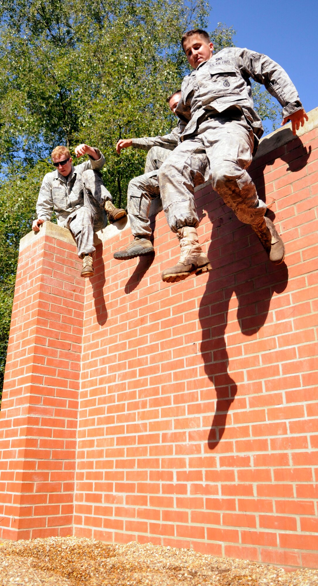 A group of Airmen from the 100th Security Forces Squadron 2009 Air Mobility Rodeo team jump down from a wall while completing an obstacle course at the British army’s Stanford Training Area July 10.  (U.S. Air Force photo by Staff Sgt. Austin M. May)
