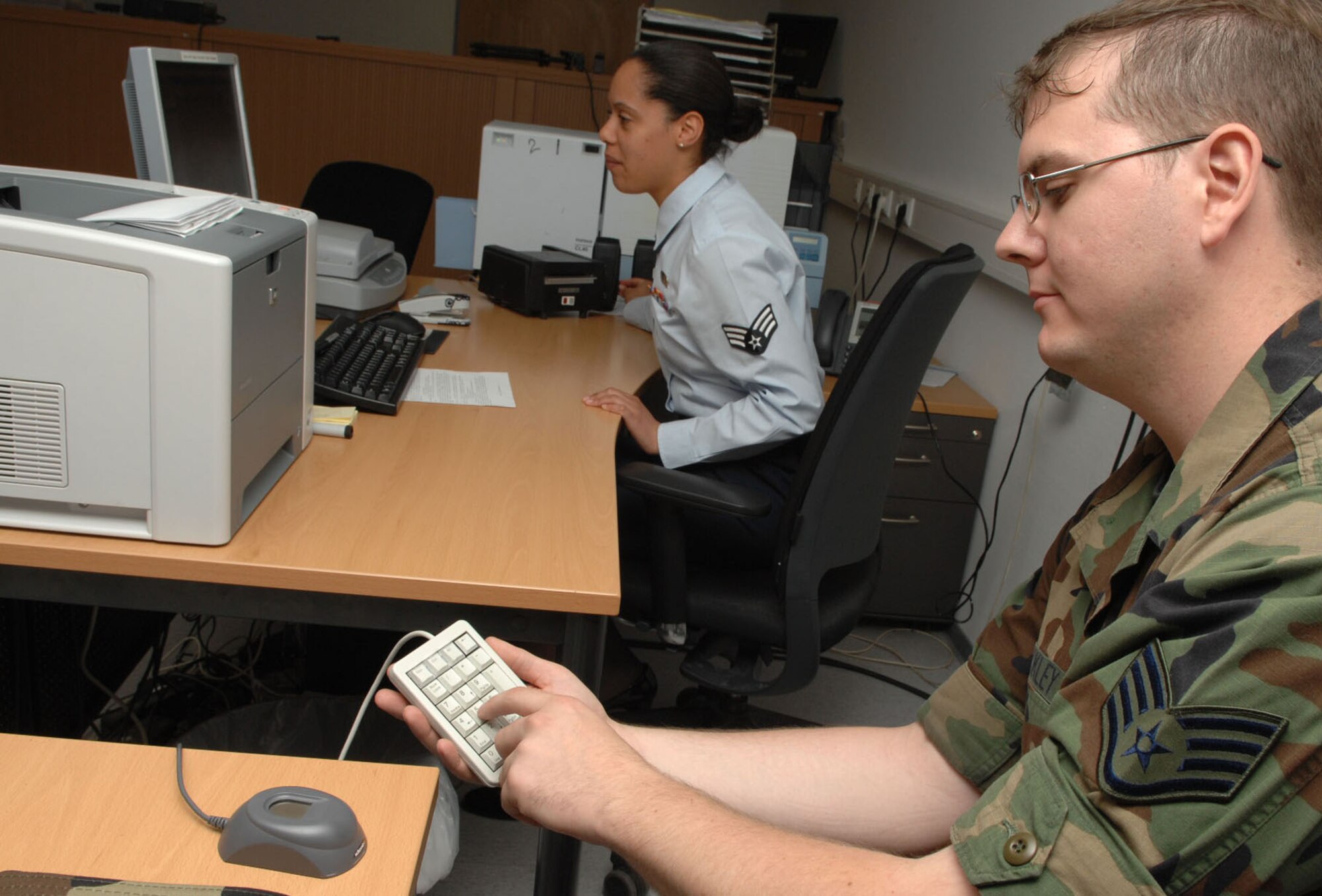 SPANGDAHLEM AIR BASE, Germany – Staff Sgt. Matthew Buckley, 52nd Equipment Maintenance Squadron, types his pin number as Senior Airman Emmanuelle Canty, 52nd Force Support Squadron, in-processes him July 6. All Airmen are required to in-process through the force support squadron upon arrival at their new duty station. (U.S. Air Force photo by Airman 1st Class Nicholas Wilson)