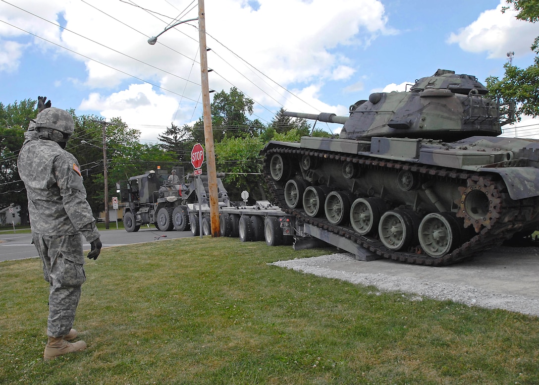 A U.S. Army soldier guides fellow soldiers to off-load an M60 Patton Tank from a vehicle designed to transport heavy equipment at the National Guard Armory in Bluffton, Ind., June 30. The M-60 Patton tank is used as a static display at the Armory and was used as a training aid to prepare the 2025th Transportation Company for deployment to Iraq.