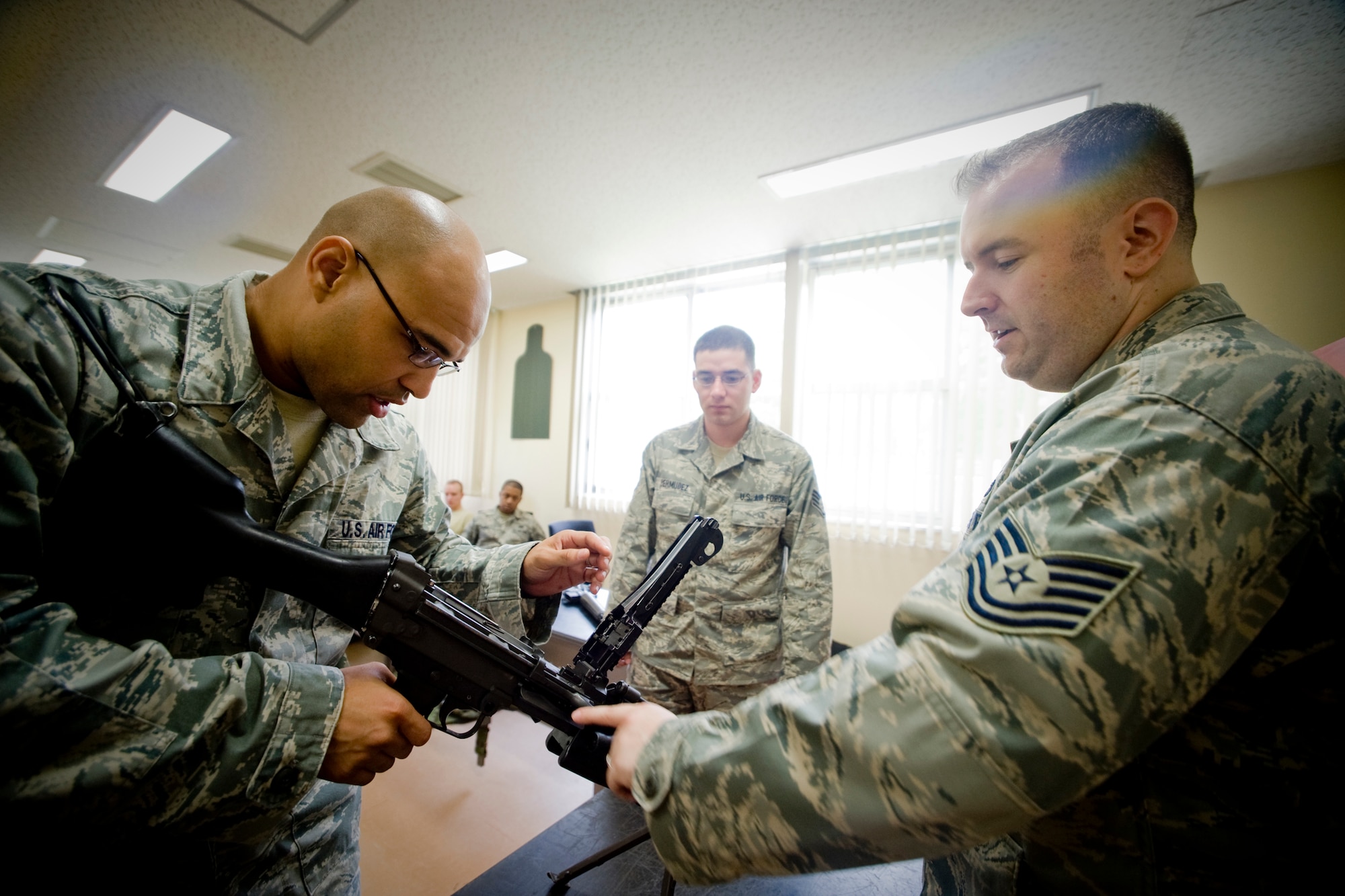 MISAWA AIR BASE, Japan -- Tech. Sgt. Robert Slagle, 35th Security Forces Squadron combat arms NCO in charge, allows Staff Sgt. James White, 35th Logistics Readiness Squadron aircraft parts store supervisor, to examine the functionality of an M249 Squad Automatic Weapon July 9. Sergeant White is one of a group of Airmen selected from the wing to support the 35th Security Forces Squadron as an augmentation force. (U.S. Air Force photo/Senior Airman Jamal D. Sutter) 