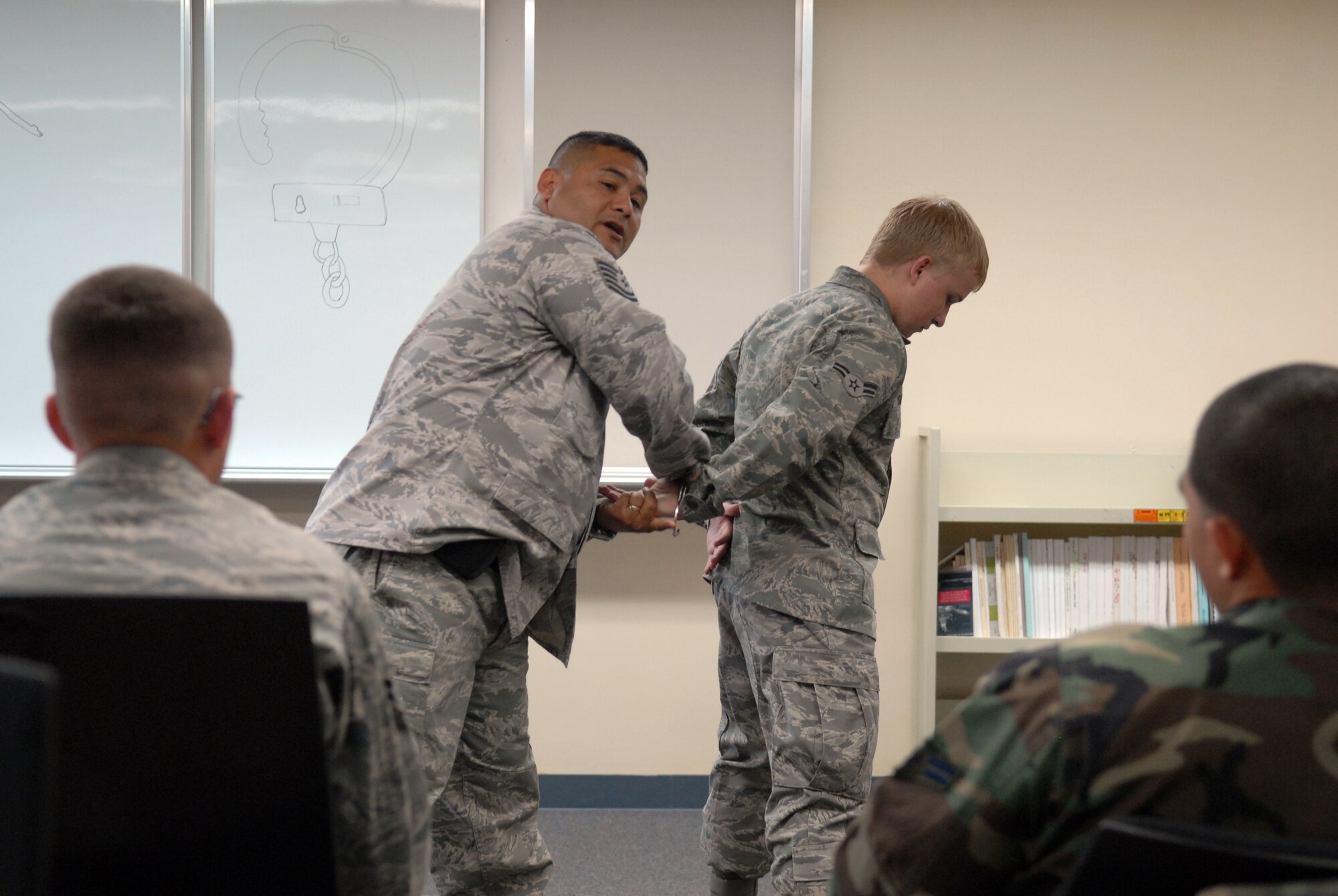 MISAWA AIR BASE, Japan -- Tech. Sgt. Christopher Padron, 35th Security Forces Squadron flight sergeant, demonstrates the proper way to detain and handcuff a suspect July 8 at the security forces building. Airmen and sailors learn the proper use of handcuffs during a five day augmentation force program. (Air Force photo/Staff Sgt. Phillip Butterfield)