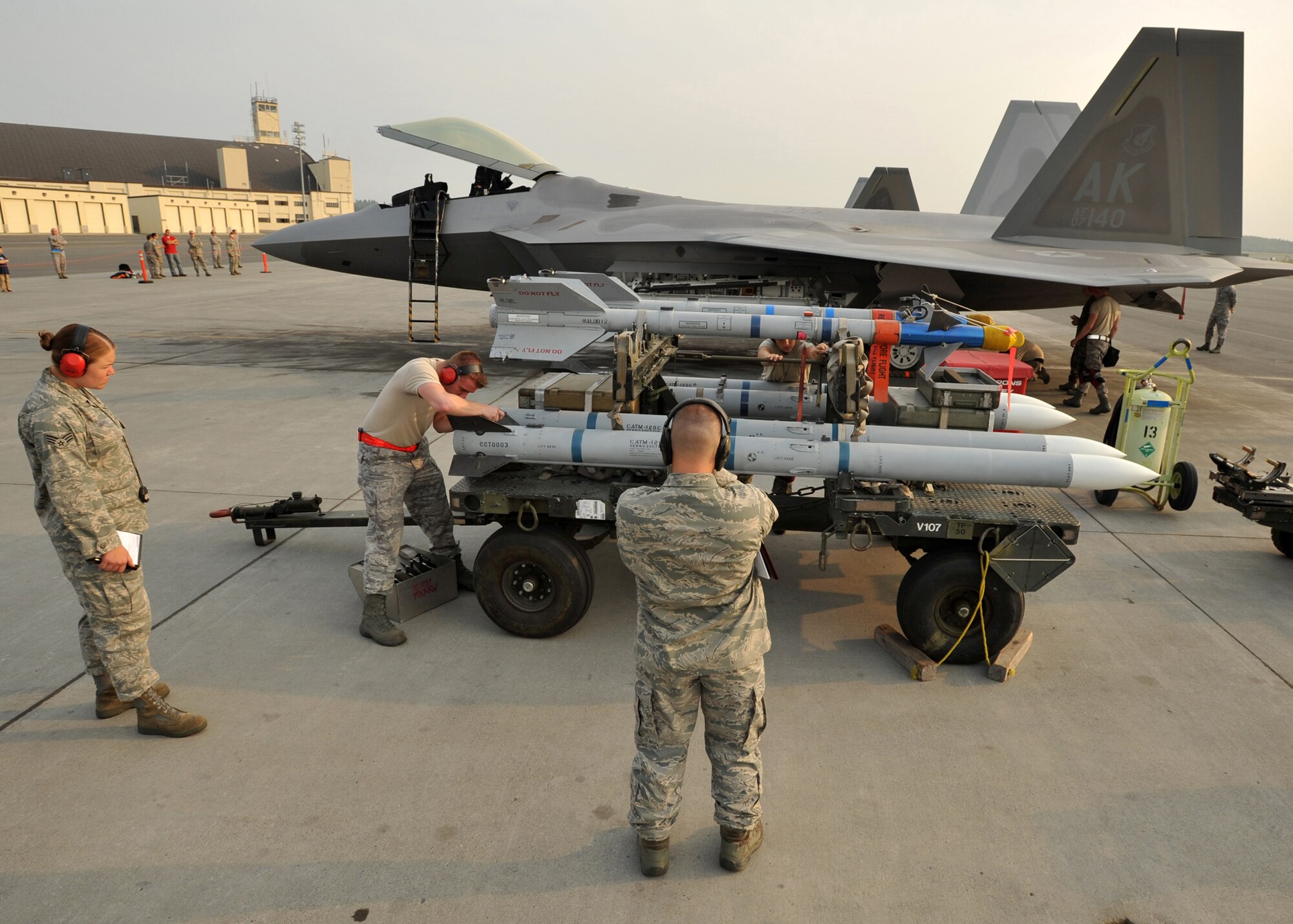 ELMENDORF AIR FORCE BASE, Alaska -- Airman 1st Class Daniel Kok installs an AIM-120 missile wing while evaluators Senior Airman Meghan Jarvis and Master Sgt. Francis Clement look on during a load crew competition July 10. The purpose of the competition is to demonstrate and be tested on quick turn weapon loads. Kok is a member of the 3rd Aircraft Maintenance Squadron. Jarvis and Clement are members of the 3rd Maintenance Group. (U.S. Air Force photo/Senior Airman Laura Turner)