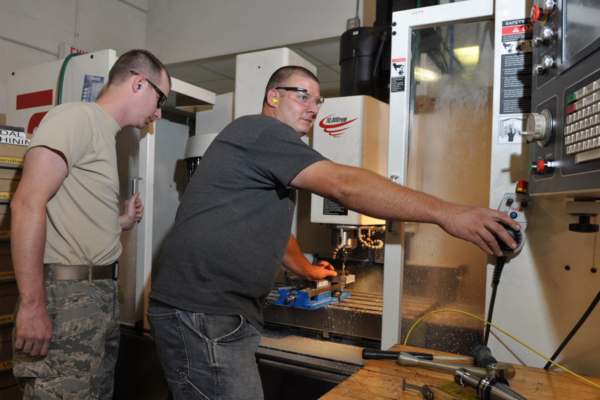 Staff Sgt. Drew Shield, 2nd Maintenance Squadron, watches attentively as Staff Sgt. Zachary Perry, an Air Reserve Technician with the 917th Maintenance Squadron instructs him on the procedures for setting tools in the Fadal CNC Machining Center, July 14, 2009, at Barksdale Air Force Base, La. The Machining Center is a completely programmable Milling machine used to fabricate Non-procurable Aircraft components for the B-52 and A-10 aircraft, ground support equipment. It is also used to manufacture custom tooling for many aircraft support specialist. Shop personnel are qualified to completely program the machine using Feature cam which is a CADCAM system used widely in civilian industries and the Air Force. Sergeant Shield is one of the first of seven Regular Air Force personnel from the 2nd Bomb Squadron at Barksdale scheduled to work alongside Reservists at the 917th Wing as a part of the Air Force’s Total Force Integration Plan, which brings together National Guardsmen with Reserve and Regular Air Force Airmen. Both Sergeants Shield and Perry are Metals Technology Craftsmen. (U.S. Air Force photo/Tech. Sgt. Jeff Walston)