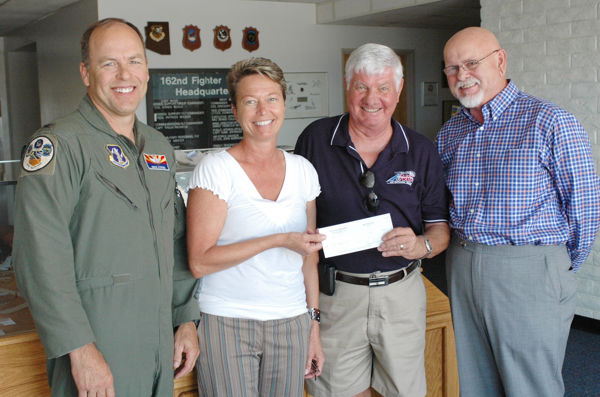(From the left) Col. Greg Stroud, 162nd Fighter Wing commander, and Barb Gavre, Family Readiness coordinator, accept a check for $606 from Hans Boensel and Michael Leigh of the Green Valley Elks Lodge #2592, July 12. The donation to Family Readiness will help the wing take care of families who need a little extra help and will ensure the wing is able to continue mailing care packages to deployed members. (Air National Guard photo by Capt. Gabe Johnson)
