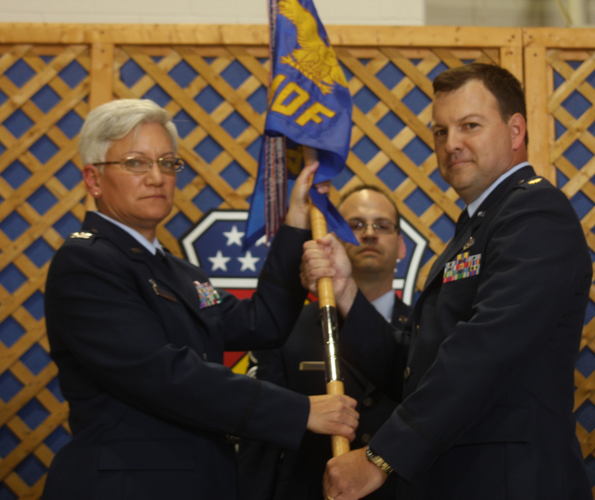 WRIGHT-PATTERSON AIR FORCE BASE, Ohio –Col. Anna Schulte, 445th Maintenance Group commander, passes the guidon to Maj. Todd Reeder, incoming Maintenance Operations Flight commander, during the July 12 Change of Command ceremony. Master Sgt. Anthony Johns, MOF first sergeant, looks on. Major Reeder was the maintenance operation officer for the 445th Aircraft Maintenance Squadron for the last seven years before assuming his new position. (Air Force photo/Senior Airman Mikhail Berlin)  