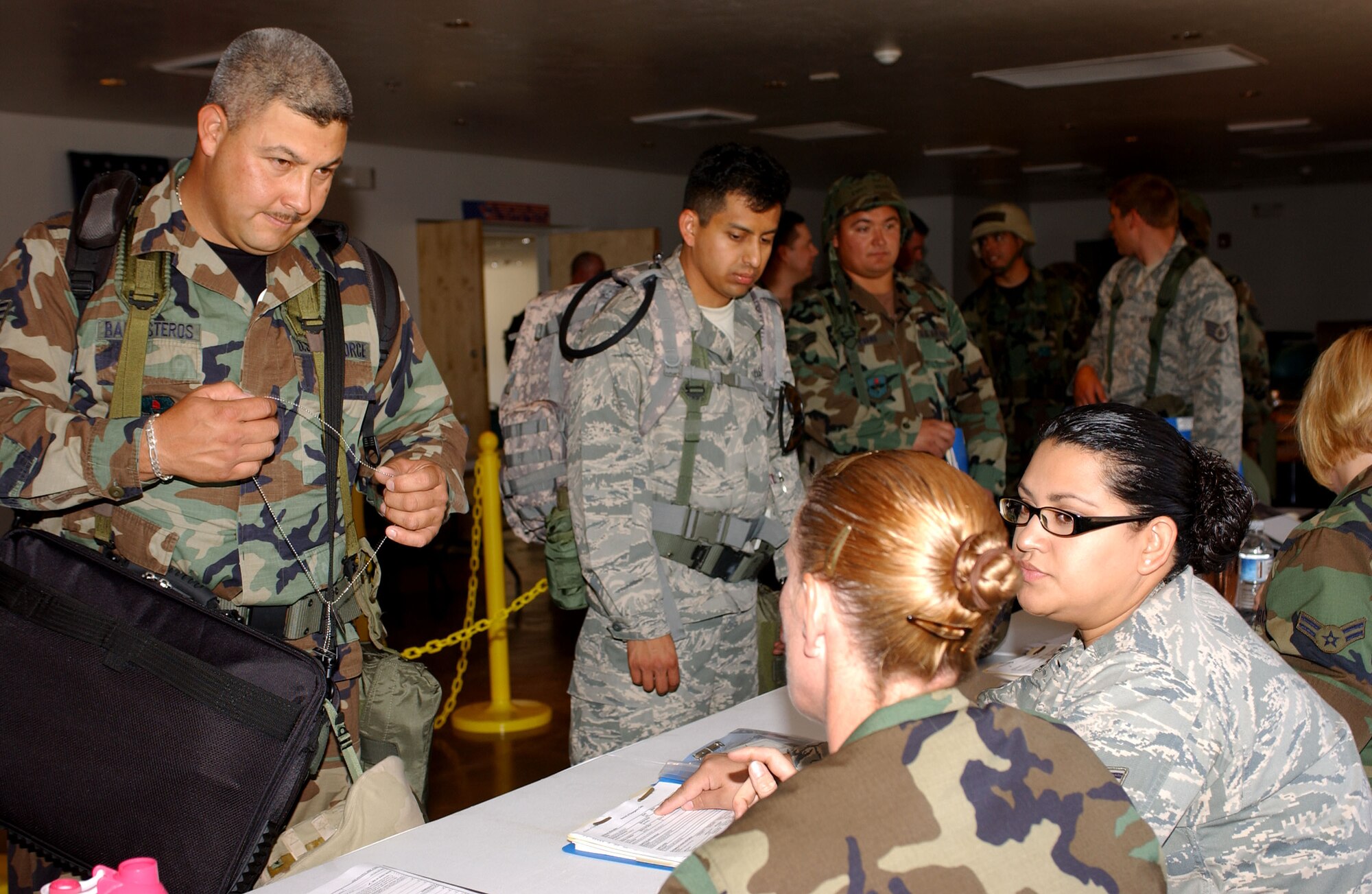 Staff Sgt. George Ballesteros (left) from the 162nd Communications Flight, walks though a pre-deployment processing line July 11, as part of a mobility exercise. Senior Master Sgt. Teresa Campbell and Staff Sgt. Maria Breceda, 162nd Force Support Squadron, check his paper work to ensure readiness. (Air National Guard photo by Staff Sergeant Sarah Elliott)