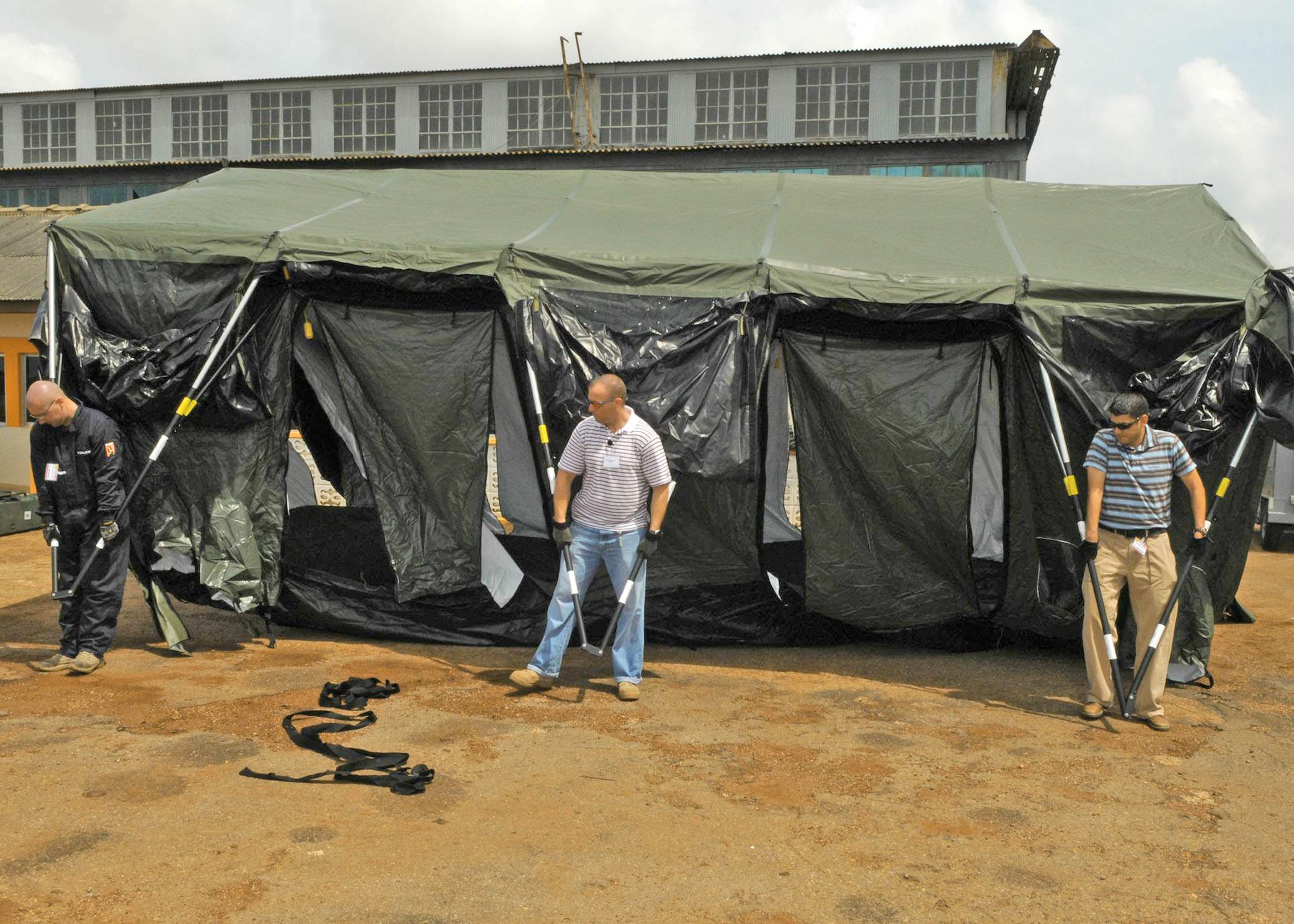 Staff James Townes, Tech. Sgt. Tracy Curtis and Capt. Daniel Hervas set up a tent at Kotoka International Airport July 1 at Accra, Ghana. The Airmen are among more than 150 Airmen, Sailors and Marines in Ghana and Sailors aboard the USS Iwo Jima who form a task force supporting President Barack Obama's visit July 10 and 11. Sergeant Townes is assigned to the 1st Combat Communications Squadron from Ramstein Air Base, Germany. Sergeant Curtis is assigned to the 621st Contingency Response Wing from McGuire Air Force Base, N.J. Captain Hervas is assigned to the 39th Logistics Readiness Squadron at Incirlik Air Base, Turkey/ (U.S. Air Force photo/Master Sgt. Jim Fisher) 