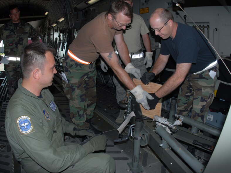 From left to right Tech. Sgt. John Martin, load master in the 249th Airlift Squadron, directs Staff Sgt. Kent Shackelford and Master Sgt. Todd Strom, both of the 119th Logistics Readiness Squadron, as they secure a piece of equipment (increment) on board an Alaska Air National Guard 249th Airlift Wing C-17 July 8, at the North Dakota Air National Guard, as they begin loading it for air lift to Volk Field, Wisc.   The
airmen are members of the newly created 119th Air Terminal Flight (also known as Aerial Port).  The increments being loaded are part of the first shipment known as a chalk for the Aerial Port at the NDANG.   (DoD photo by Senior Master Sgt. David H. Lipp) (Released)


