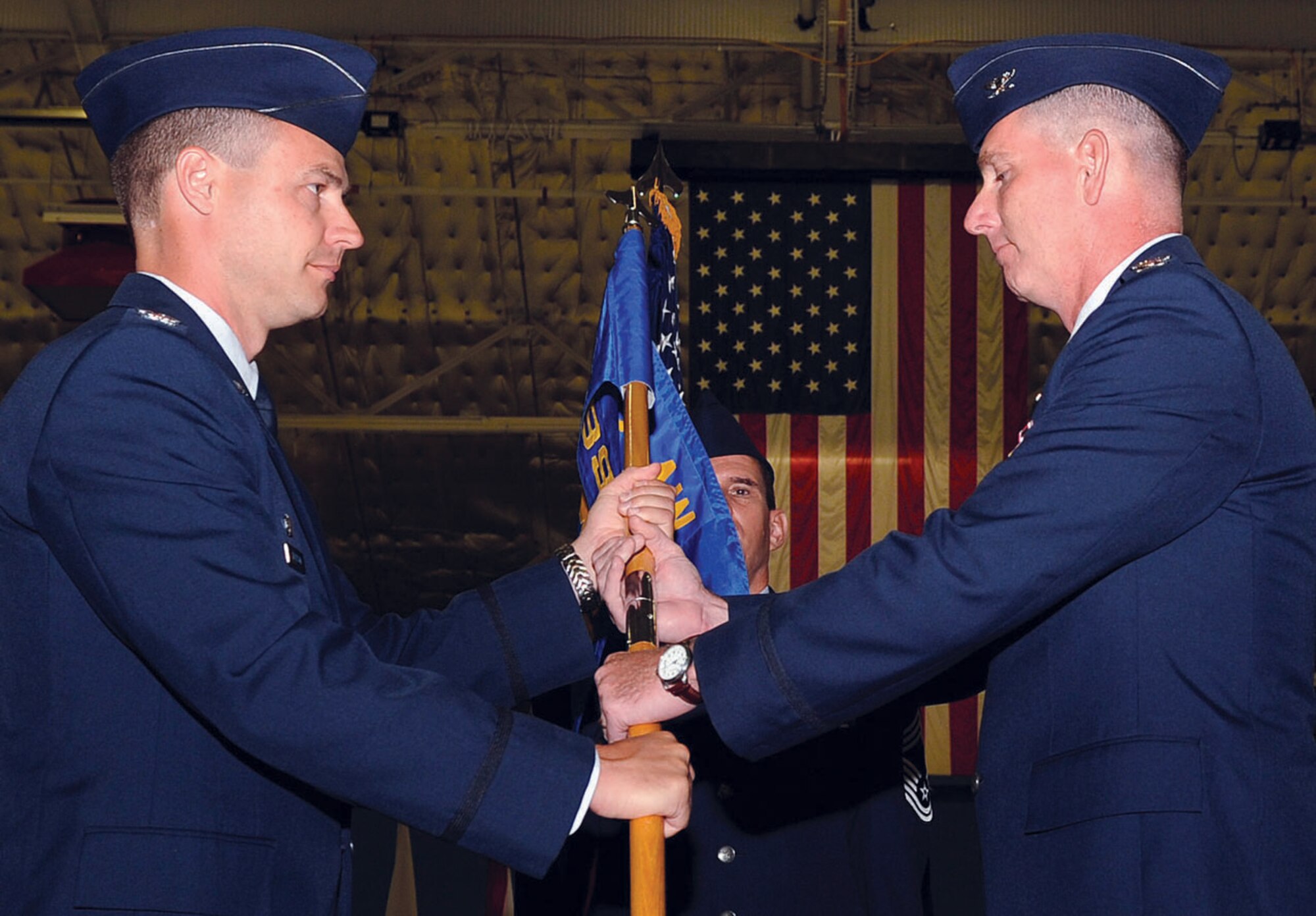 Colonel Steven Harrison, 89th Airlift Wing commander, hands the 89th Maintenance Group guidon to Col. Scott Haines, the 89th Maintenance Group commander, during a change of command ceremony in Hanger 3 Wednesday. The change of command ceremony is a time-honored tradition which symbolizes the transfer and continuity of authority as the group is passed from one commander to another. (U.S. Air Force photo/ Bobby Jones)