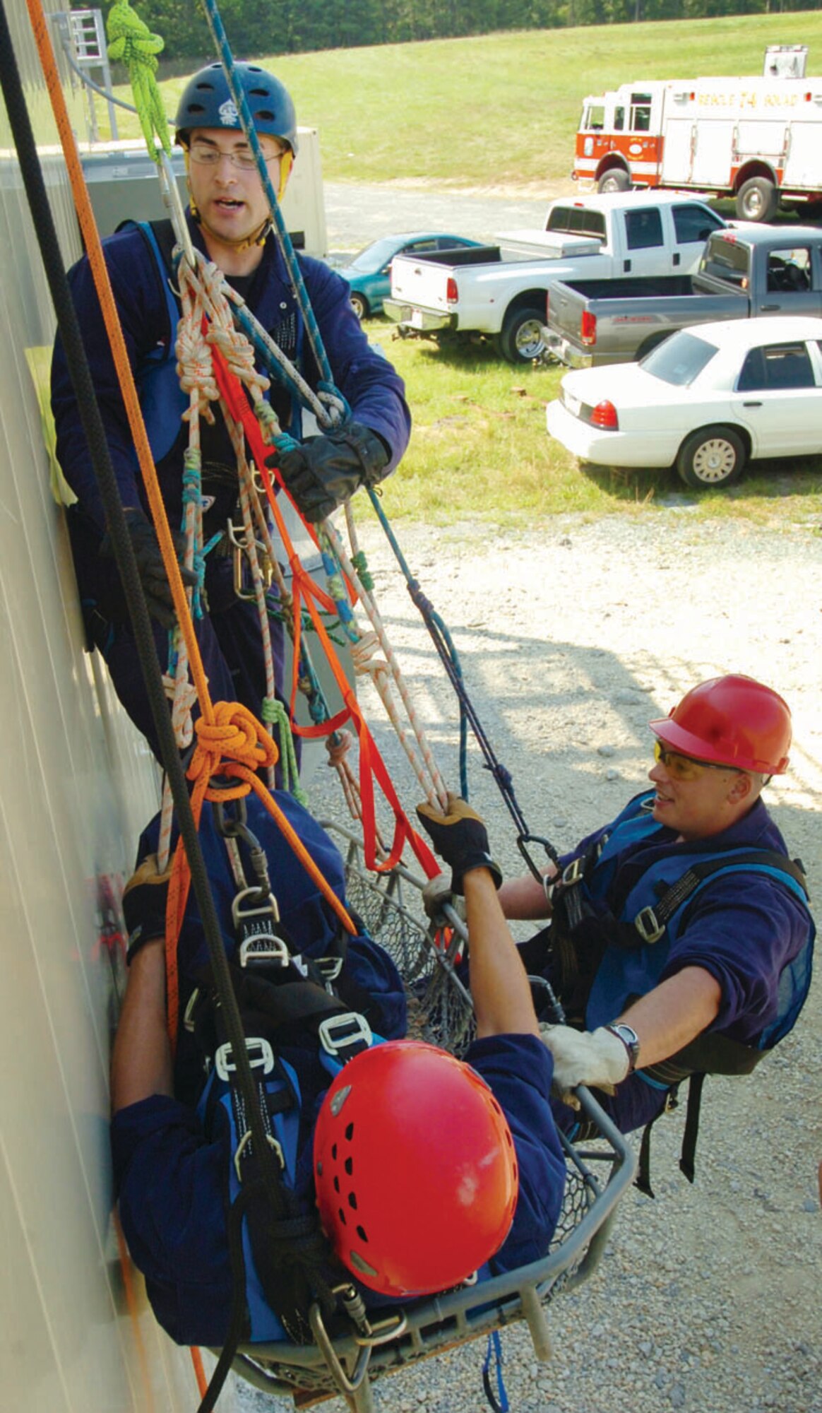 Perched high on the side of the Andrewsburn facility, 316th Civil Engineer Squadron firefighters, Senior Airman Timothy Mulvaney, standing left, works in unison with Senior Airman Justin Minton, right, to secure Airman 1st Class Steve Hjerstedt, a “spinal injury victim” into a Stokes litter basket during high angle rescue training Tuesday. The training, sponsored by Maryland Fire Rescue Institute from the University of Maryland, is just one of the specialized courses to help the Airmen acquire rescue technician certification. (U.S. Air Force photo/ Bobby Jones)