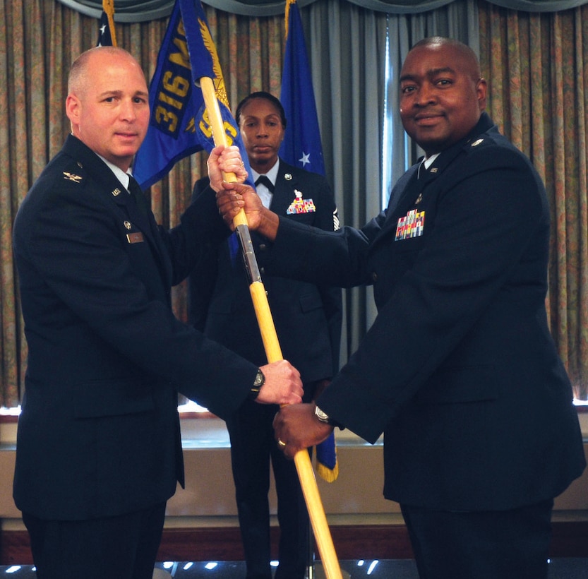 Lieutenant Col. Kevin Brooks takes the 316th Force Support Squadron guidon from Col. John W. Long, 316th Mission Support Group commander, during a change of command ceremony at The Club at Andrews Wednesday. Colonel Brooks hails from Headquarters NATO, Allied Joint Force Command, Brussum, Netherlands, and Lt. Col. Teresa Forrest, former 316 FSS commander, is headed to Tinker AFB, Ok. as the 72nd Mission Support Group deputy commander. (U.S. Air Force photo/ Senior Airman Steven R. Doty)