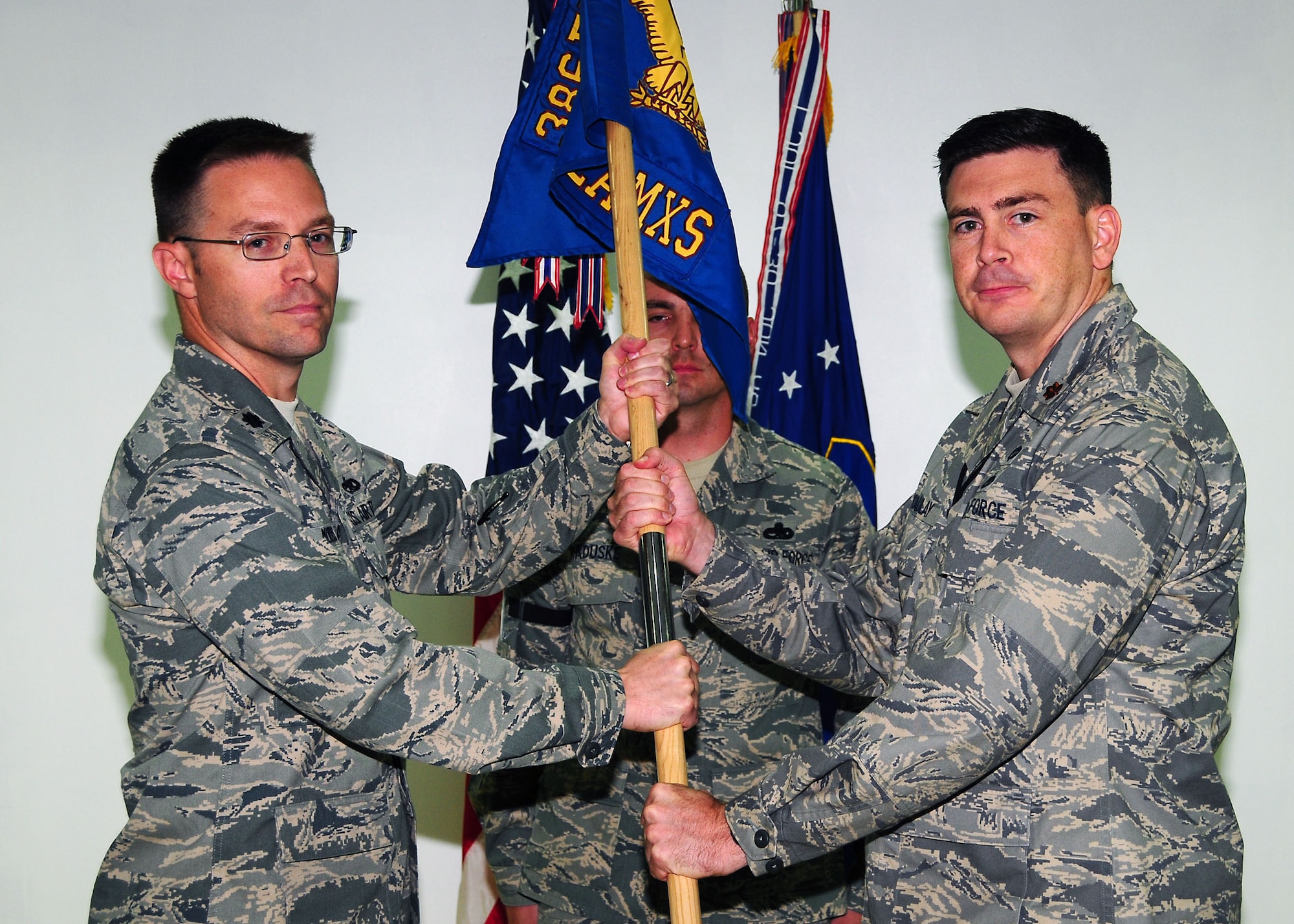 Maj. Christopher Macaulay, right, assumes command of the 386th Expeditionary Aircraft Maintenance Squadron, by accepting the guidon from Lt. Col. Colin Morris, 386th Expeditionary Maintenance Group deputy commander, during a change of command ceremony in Southwest Asia July 14. Maj. Maccaulay is deployed from Travis Air Force Base, Calif.  (U.S. Air Force photo/Tech Sgt. Tony Tolley)